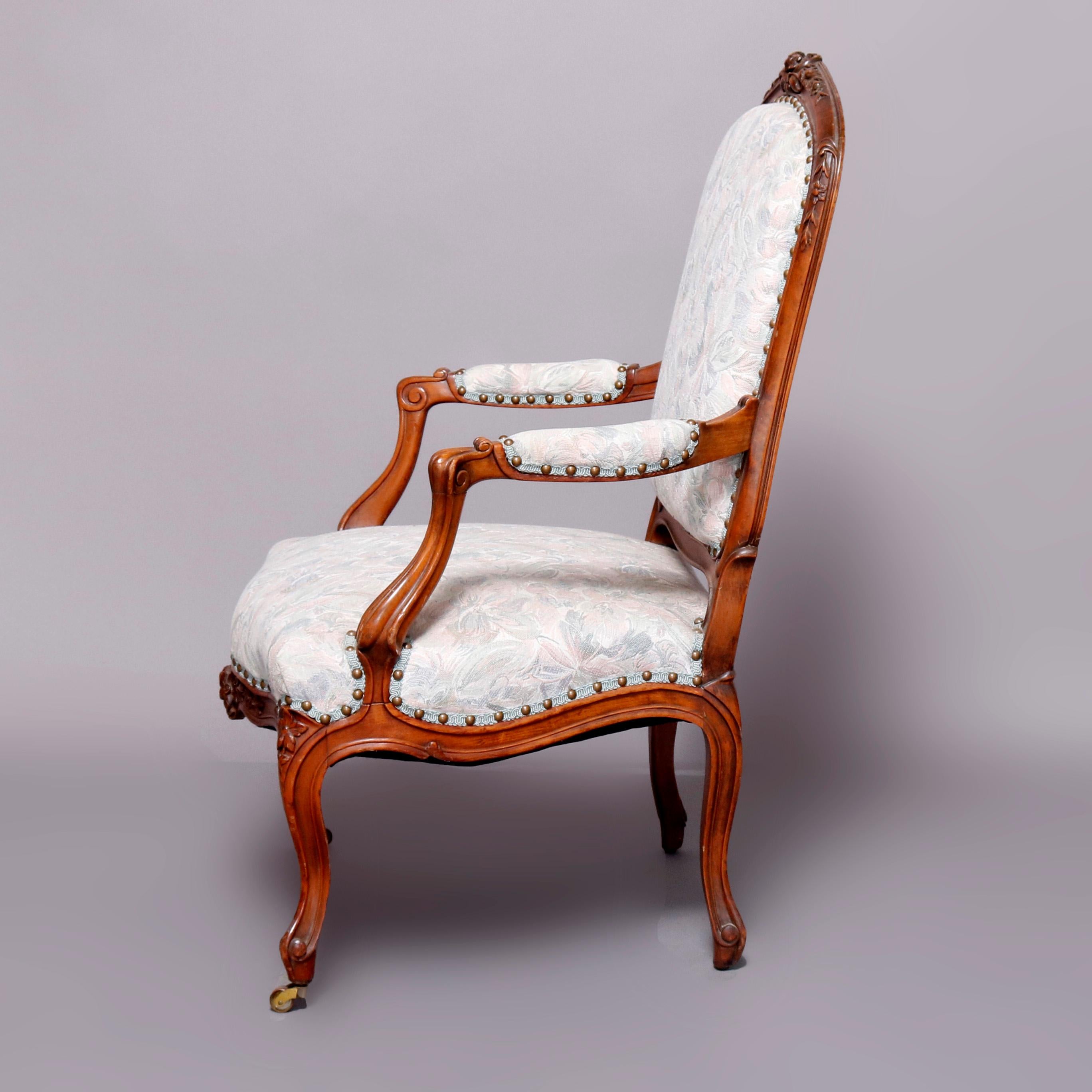 An antique French Louis XVI armchair offers fruitwood frame having floral carved crest, skirt and knees, upholstered seat, back and arms, raised on cabriole legs, 20th century

***DELIVERY NOTICE – Due to COVID-19 we are employing NO-CONTACT