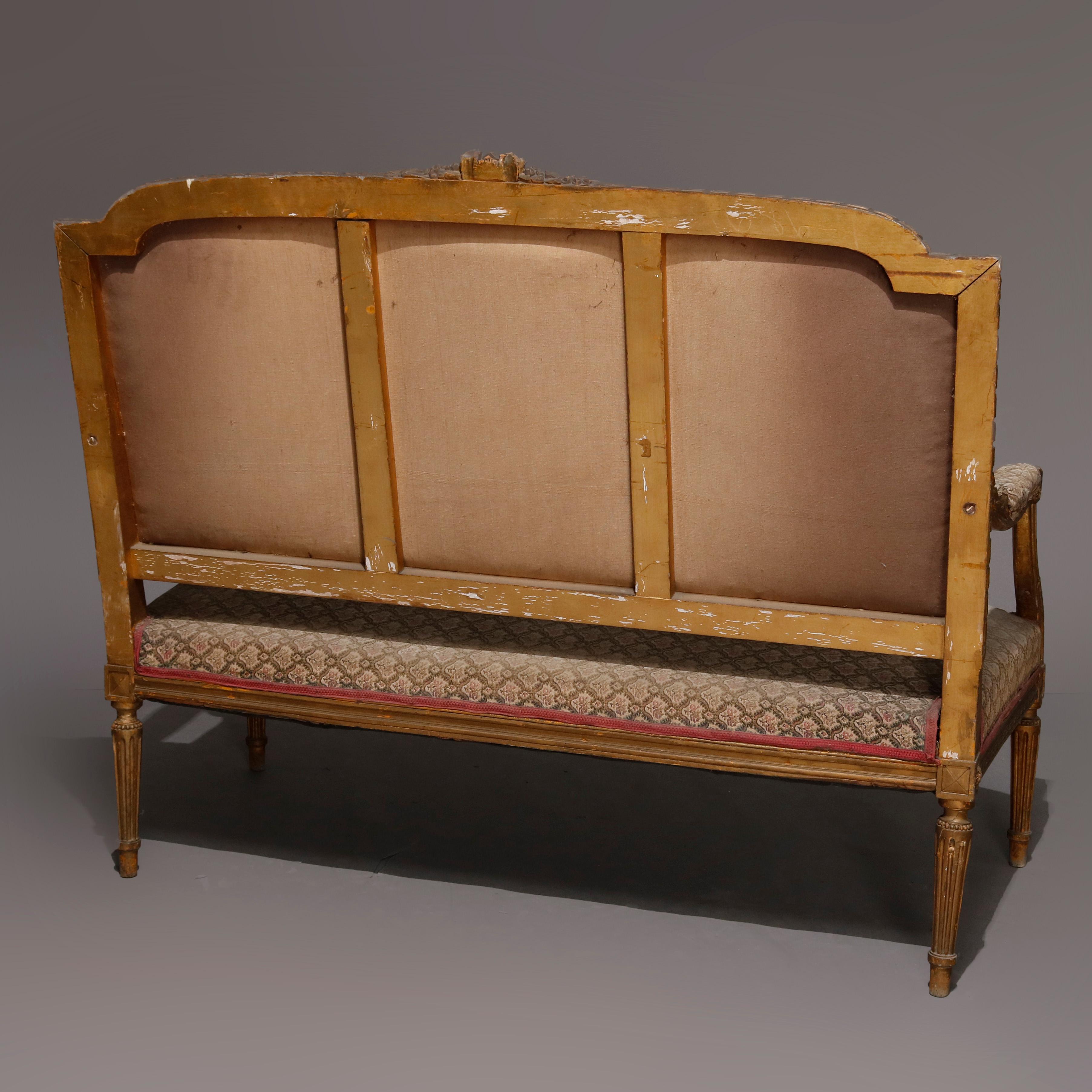 An antique French Louis XVI settee offers carved and gilt fruitwood frame with floral and foliate crest, acanthus scroll arms, rosettes and raised on reeded tapered legs, 19th century

***DELIVERY NOTICE – Due to COVID-19 we are employing NO-CONTACT