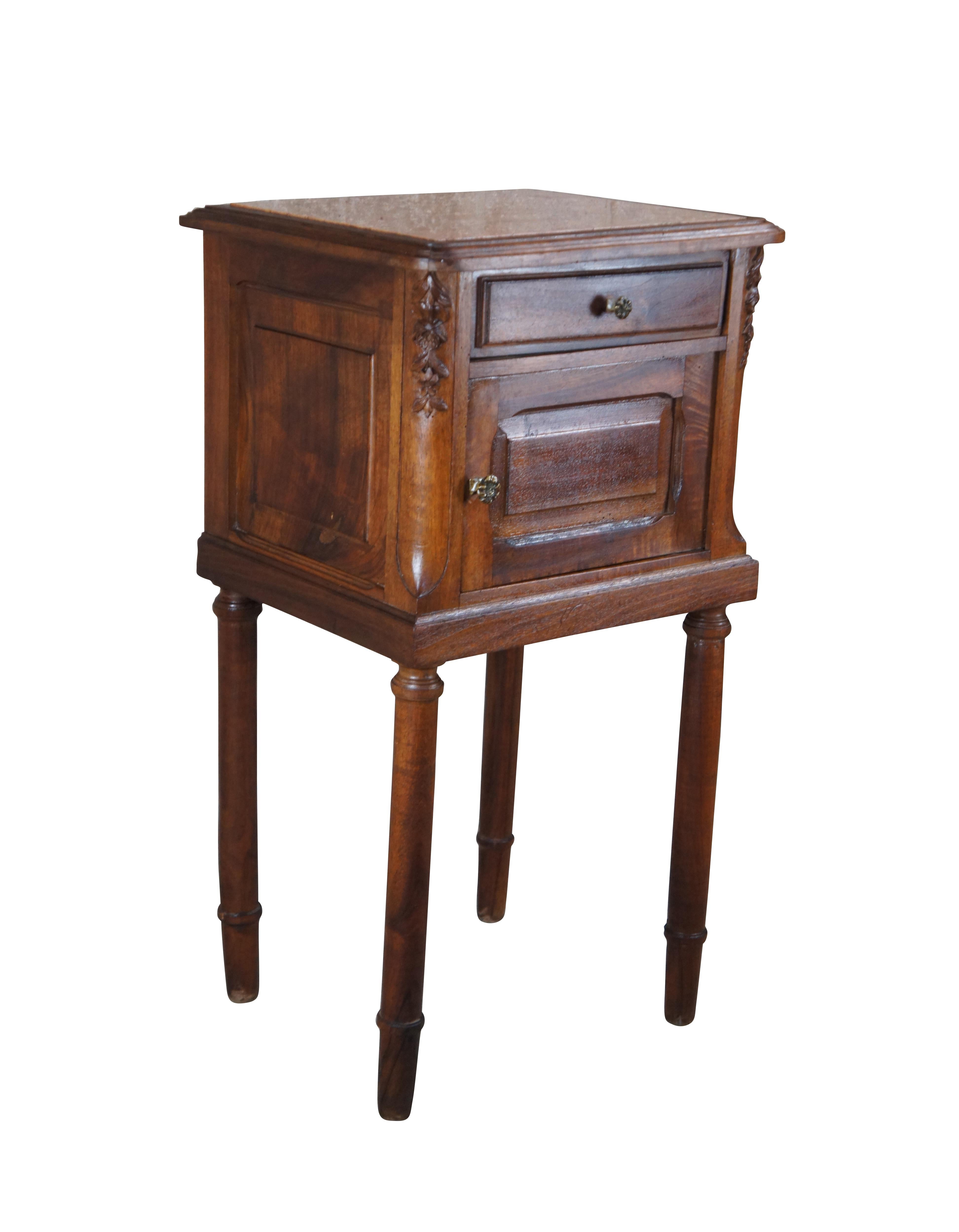 A quaint 19th century French bedside table / cabinet. Made from walnut with inset travertine top. Features a central hand dovetailed drawer made from oak and lower cabinet. Stiles are chamfered and carved with foliate motif. The cabinet rests on