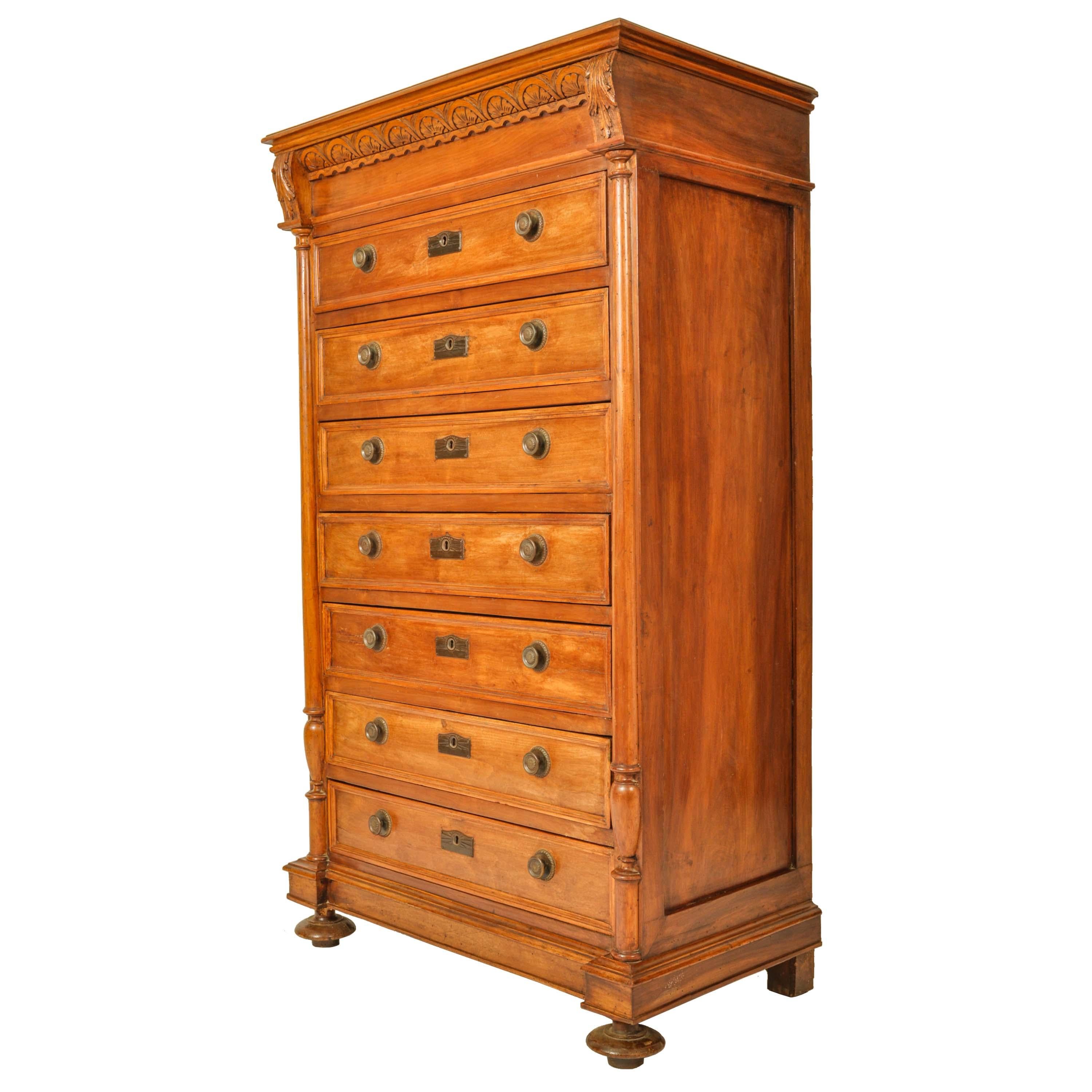 A very good antique French cherry wood Louis XVI semainier (seven drawer) chest dresser, circa 1880.
The top of the chest has a carved 'fan' shaped gallery flanked by a pair of carved acanthus leaf brackets, the chest having ring turned half