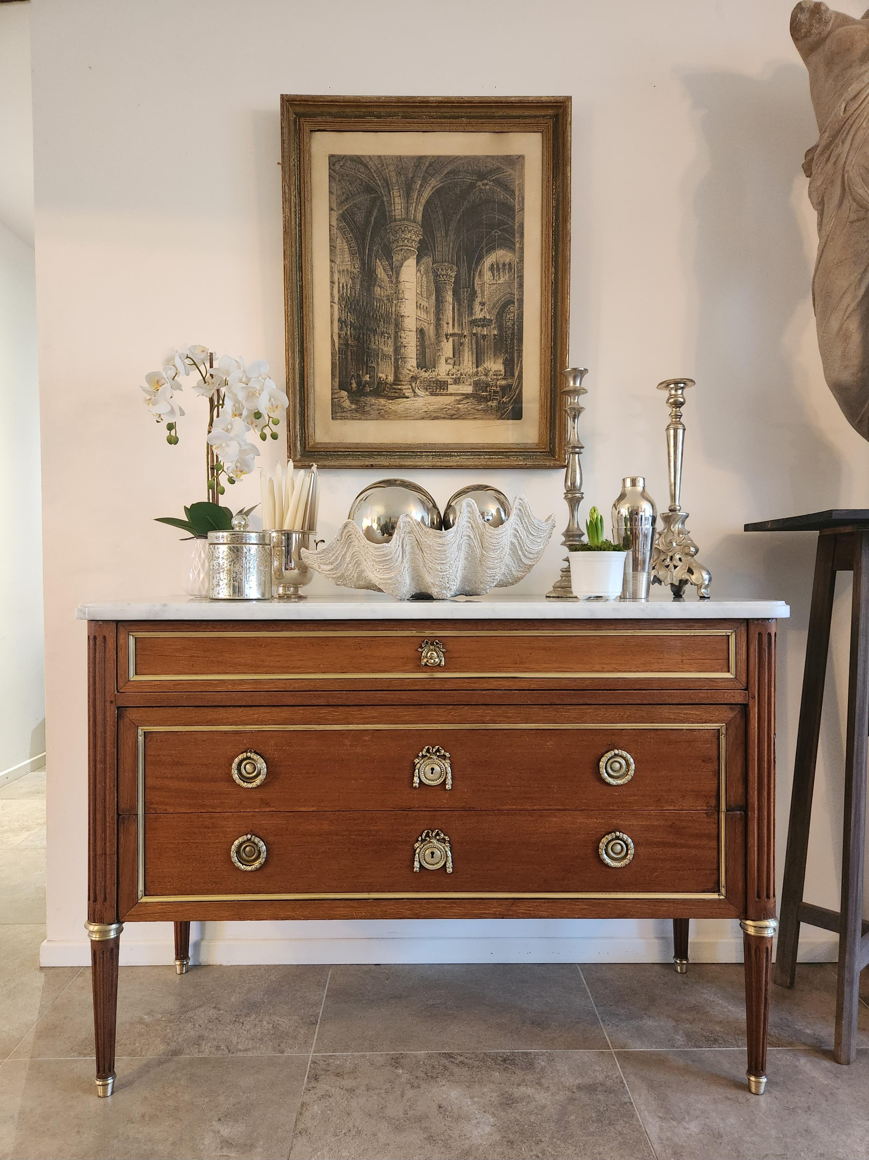 Antique French 19th Century Louis XVI Chest Of Drawers Commode sormontato da un marmo di Carrara.
Gambe scanalate rifinite con anelli e zoccoli in bronzo dorato.
Tre cassetti a coda di rondine, dettagli in bronzo e ottone.
Una chiave decorativa che