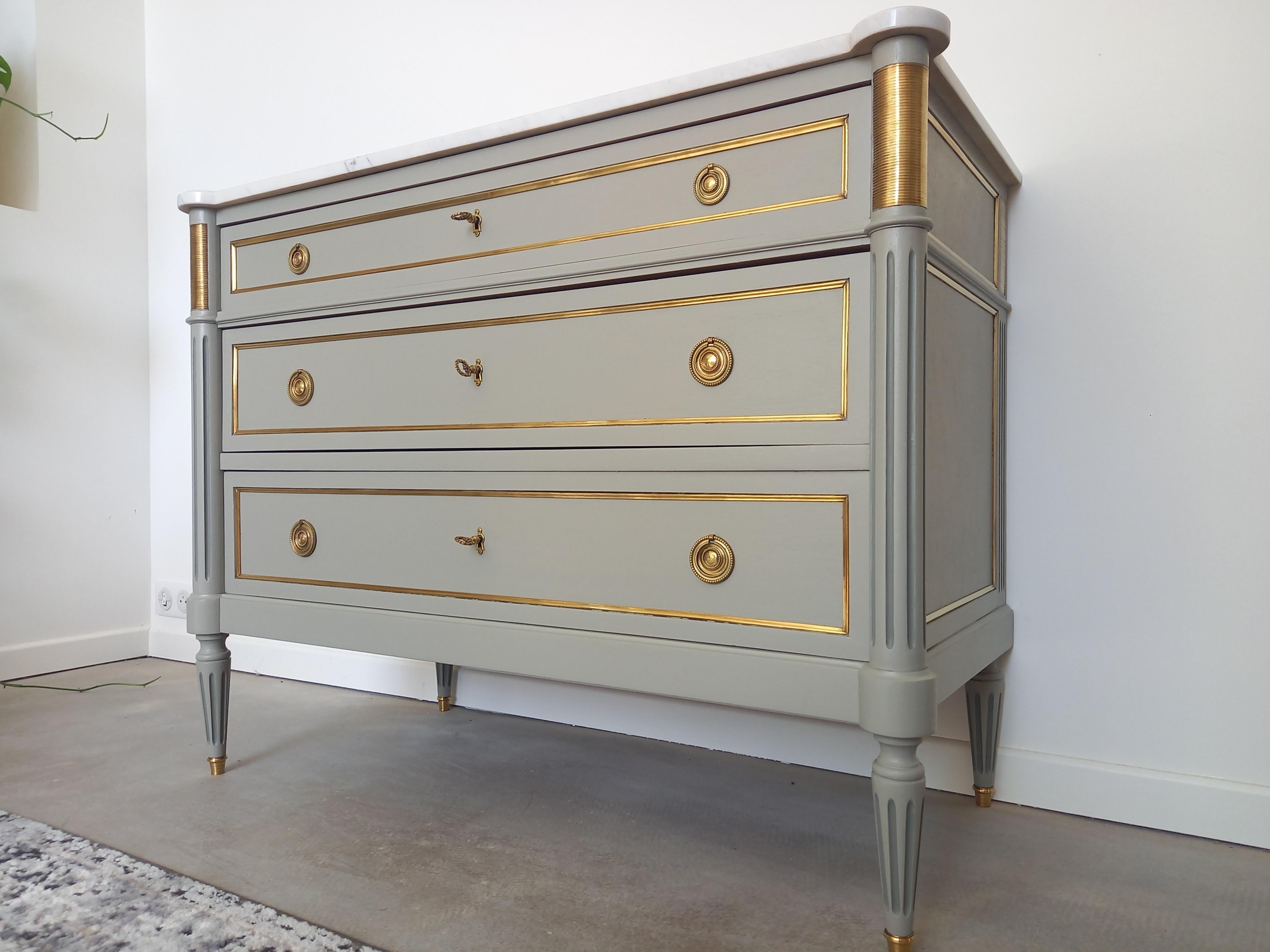 Antique French, Louis XVI style chest of drawers topped with a white Carrara marble, fluted legs finished with golden bronze clogs. 
Three dovetailed drawers with brass details, all the locks are functional and the keys are complete.
Impeccable