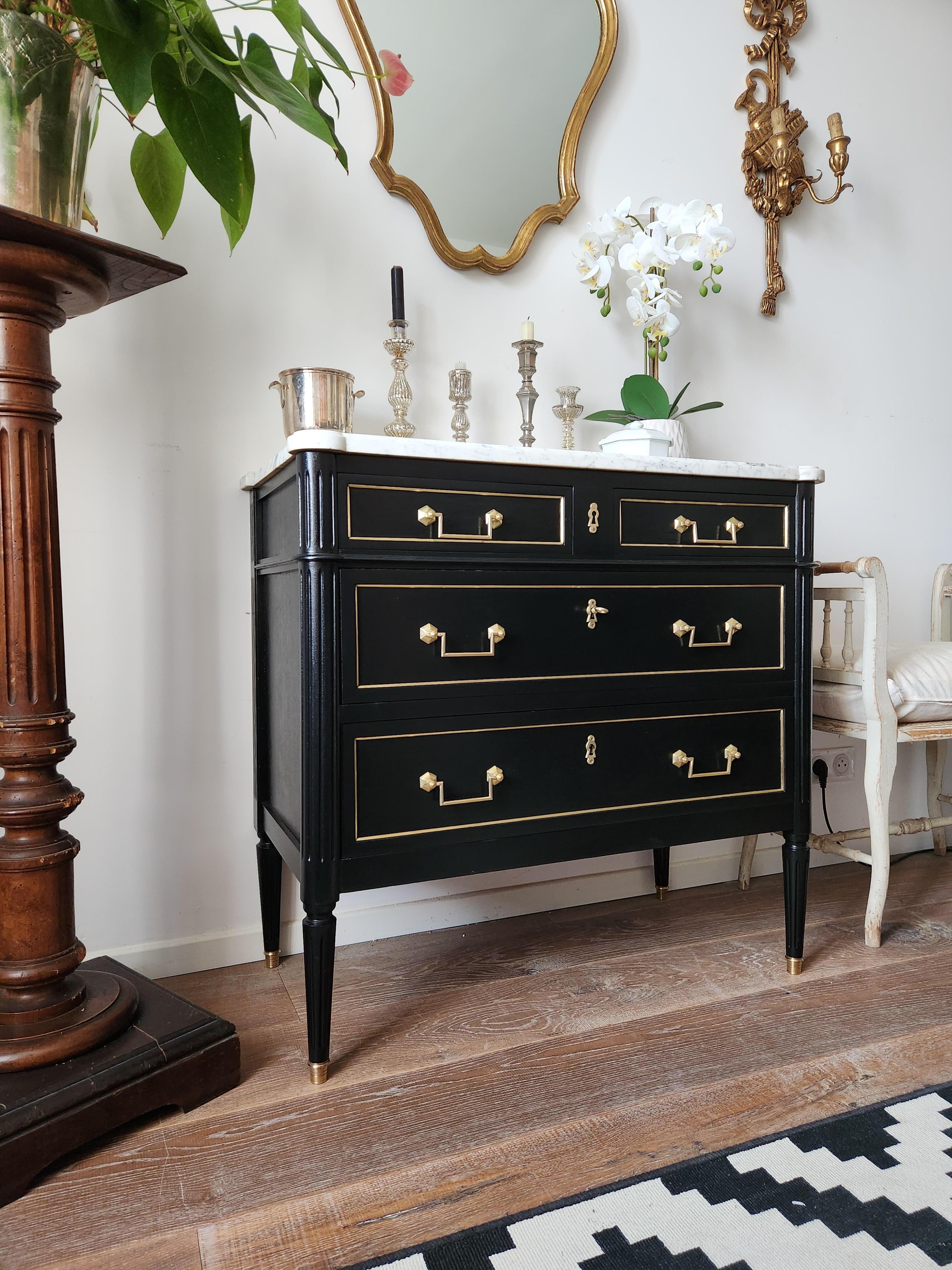 Commode ancienne française de style Louis XVI surmontée d'un marbre blanc de Carrare, pieds cannelés terminés par des sabots en bronze doré. 
Tiroirs à queue d'aronde avec détails en laiton et clé.
 