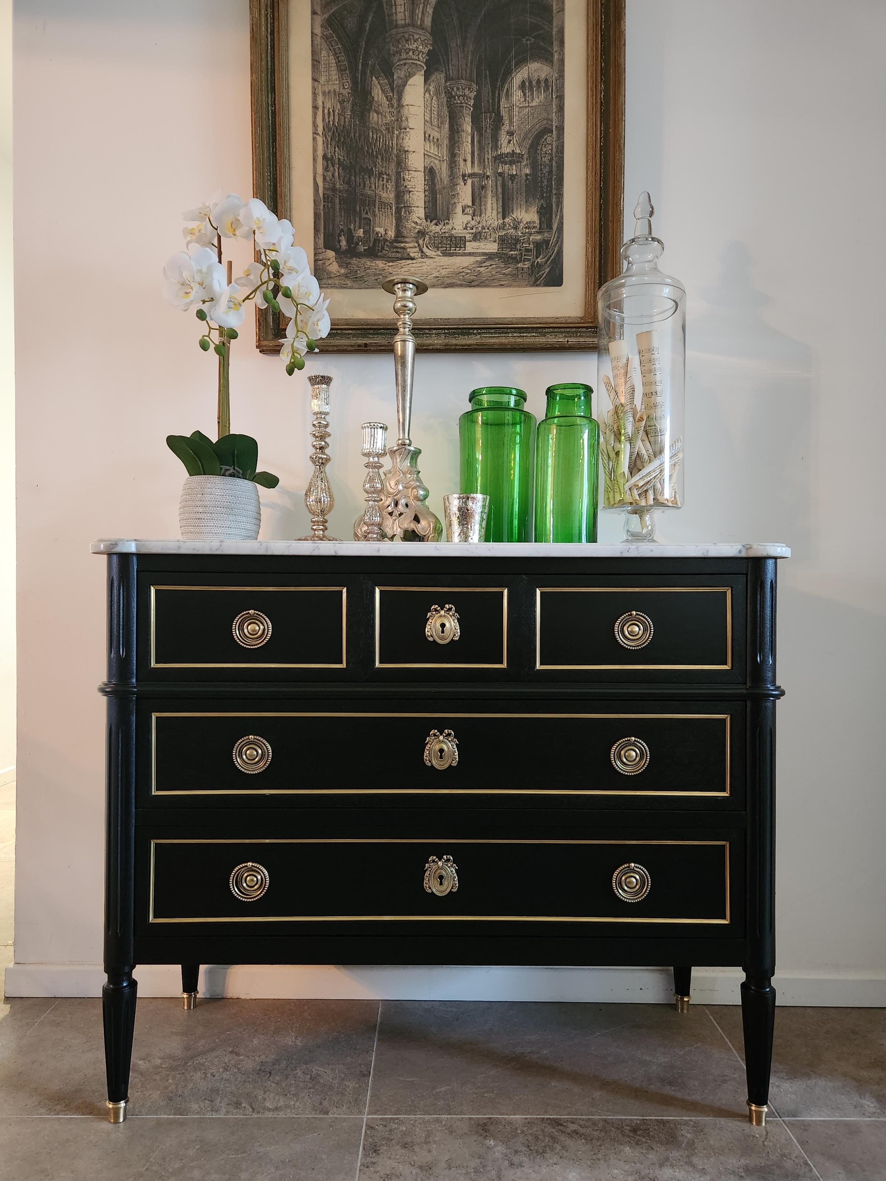 Commode ancienne française de style Louis XVI surmontée d'un marbre blanc de Carrare, pieds cannelés terminés par des sabots en bronze doré. 
Tiroirs à queue d'aronde avec détails en laiton et clé.
 