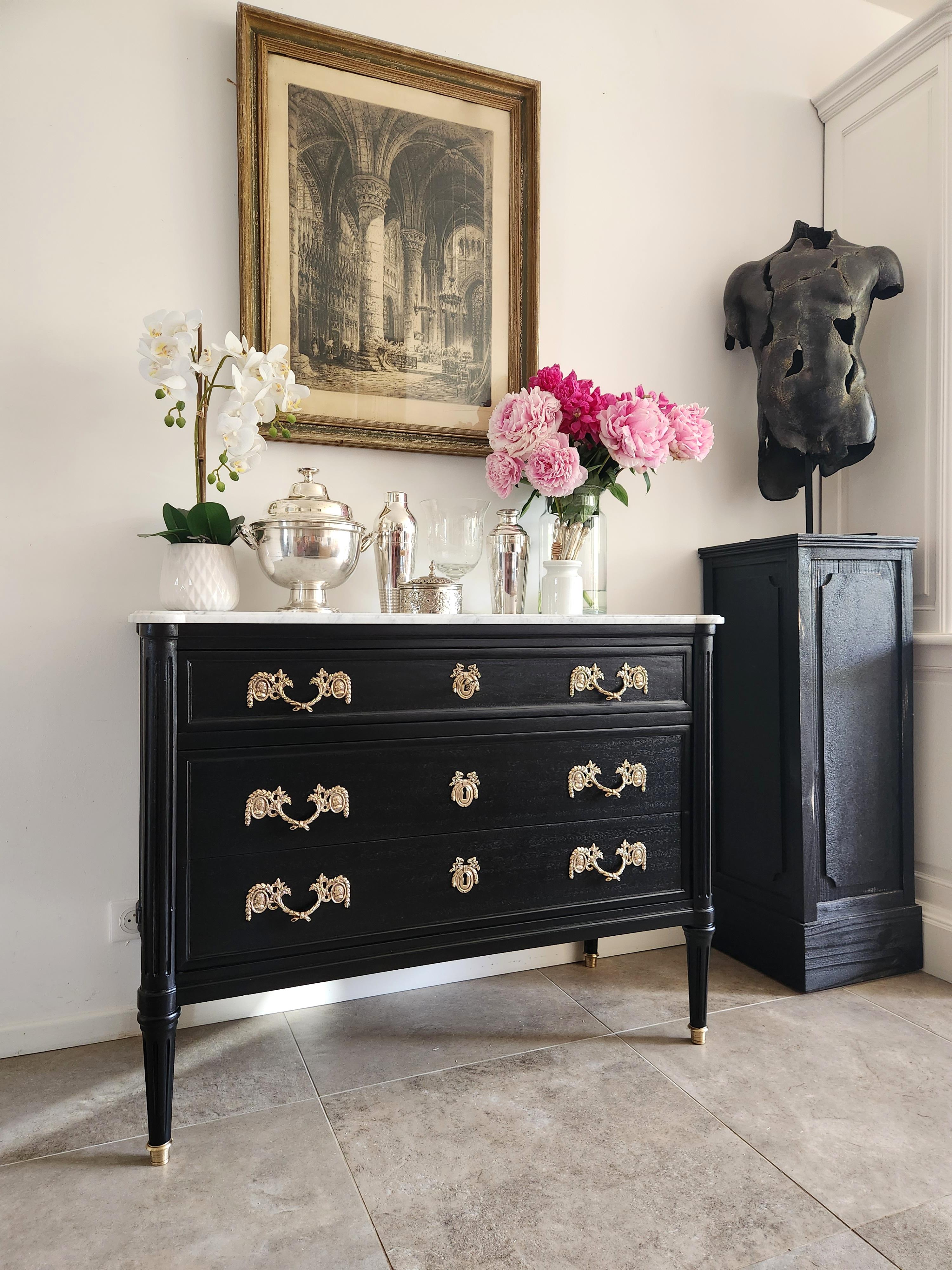 Antique 19th French, Louis XVI style chest of drawers topped with a white Carrara marble, fluted legs finished with golden bronze clogs. 
Dovetailed drawers with brass details, and a key.

 The bronze handles connect two medallions in which two male