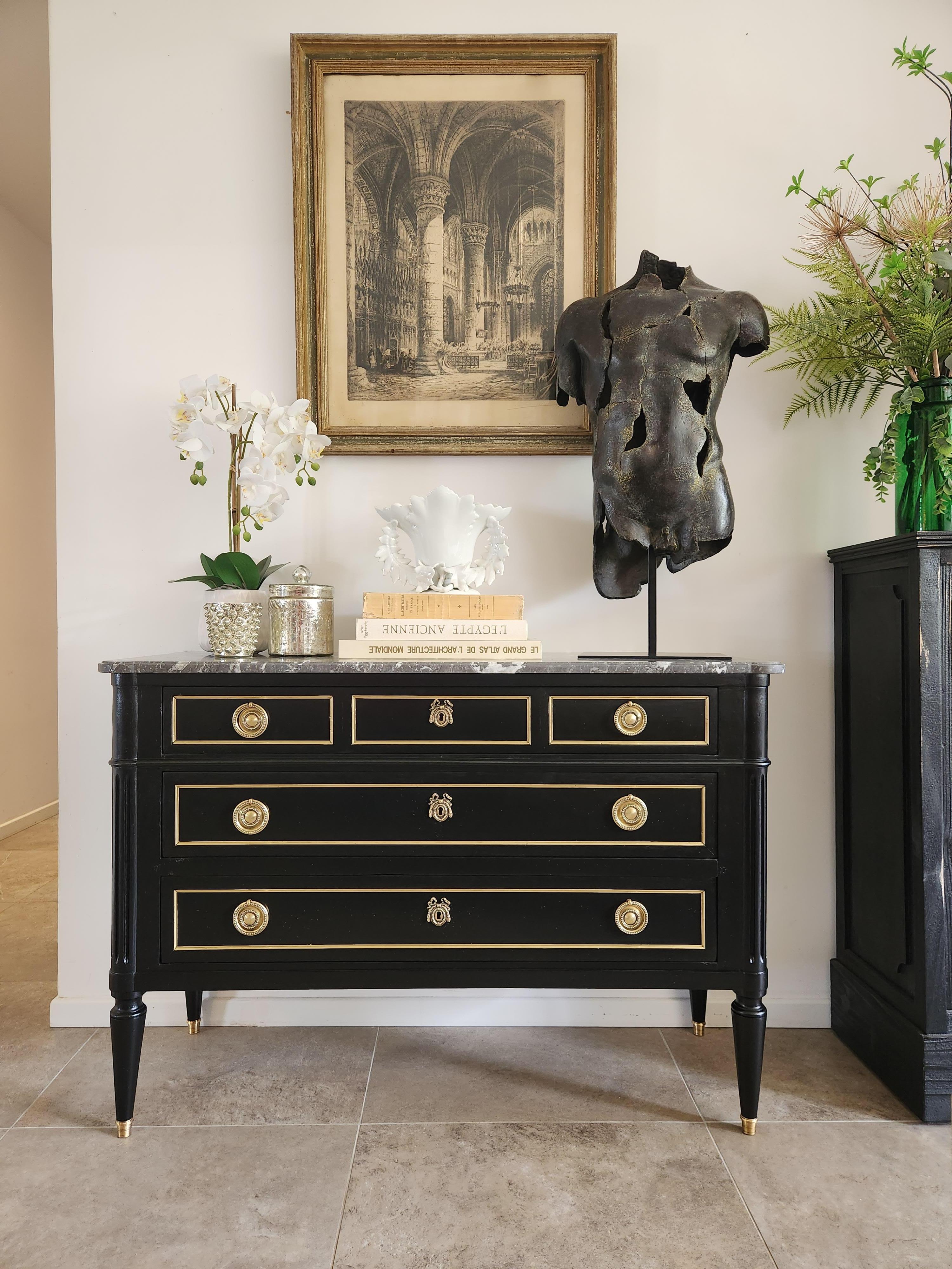 Antique French Louis XVI style chest of drawers topped with a grey marble, fluted legs finished with golden bronze clogs. 
Dovetailed drawers with brass details, and a key.
The photos and video accurately describe the good condition of the piece.