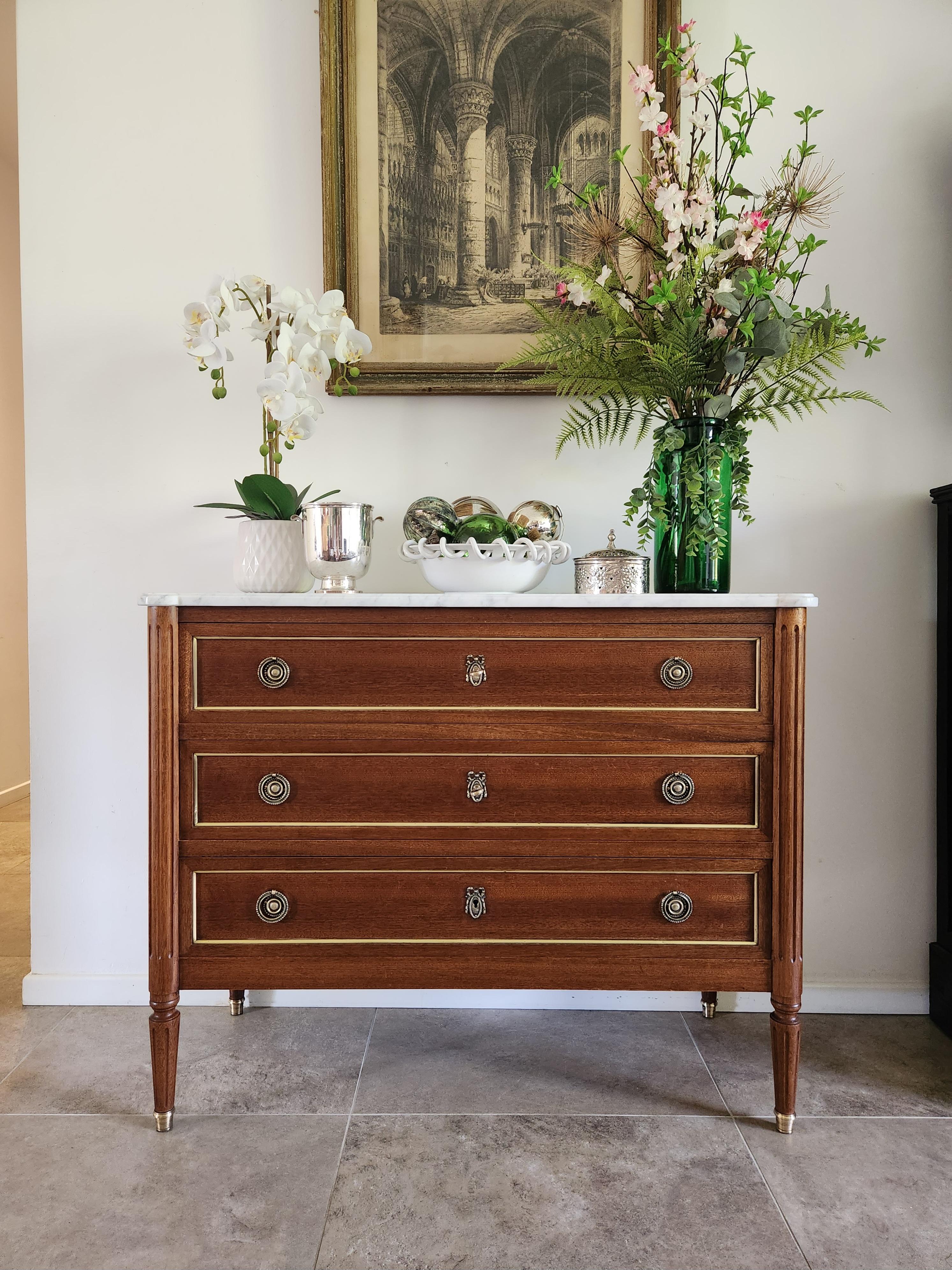 Antique French, Louis XVI style chest of drawers topped with a white Carrara marble, fluted legs finished with golden bronze clogs. 
Three dovetailed drawers with bronze and brass details, two keys.

 
The photos and video accurately describe the