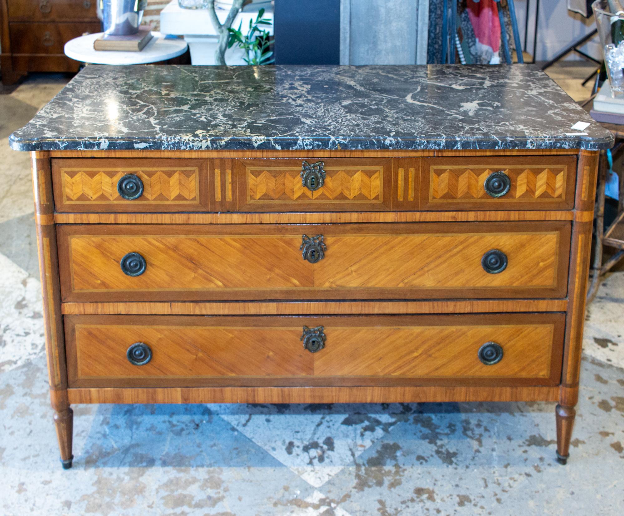 This beautifully decorated three-drawer commode features a Belgian marble top and stunning veneer marquetry on the drawer-fronts and sides. The top has rounded front corners and plenty of movement in the marble coloring. The hardware consists of