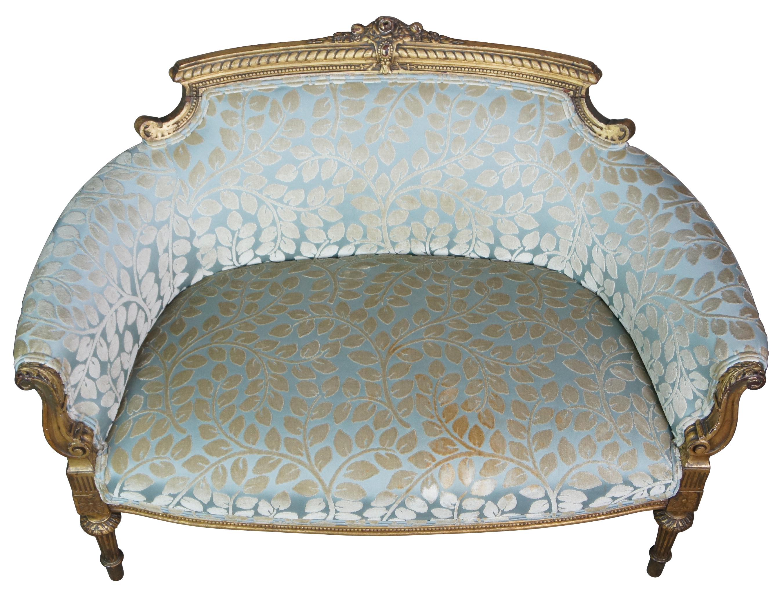 A quaint mid-19th century French settee. Features a flared and carved giltwood frame with a light blue upholstering featuring a raised white velour floral leaf pattern. Includes classical Louis XVI motifs with floral medallions, turned and tapered