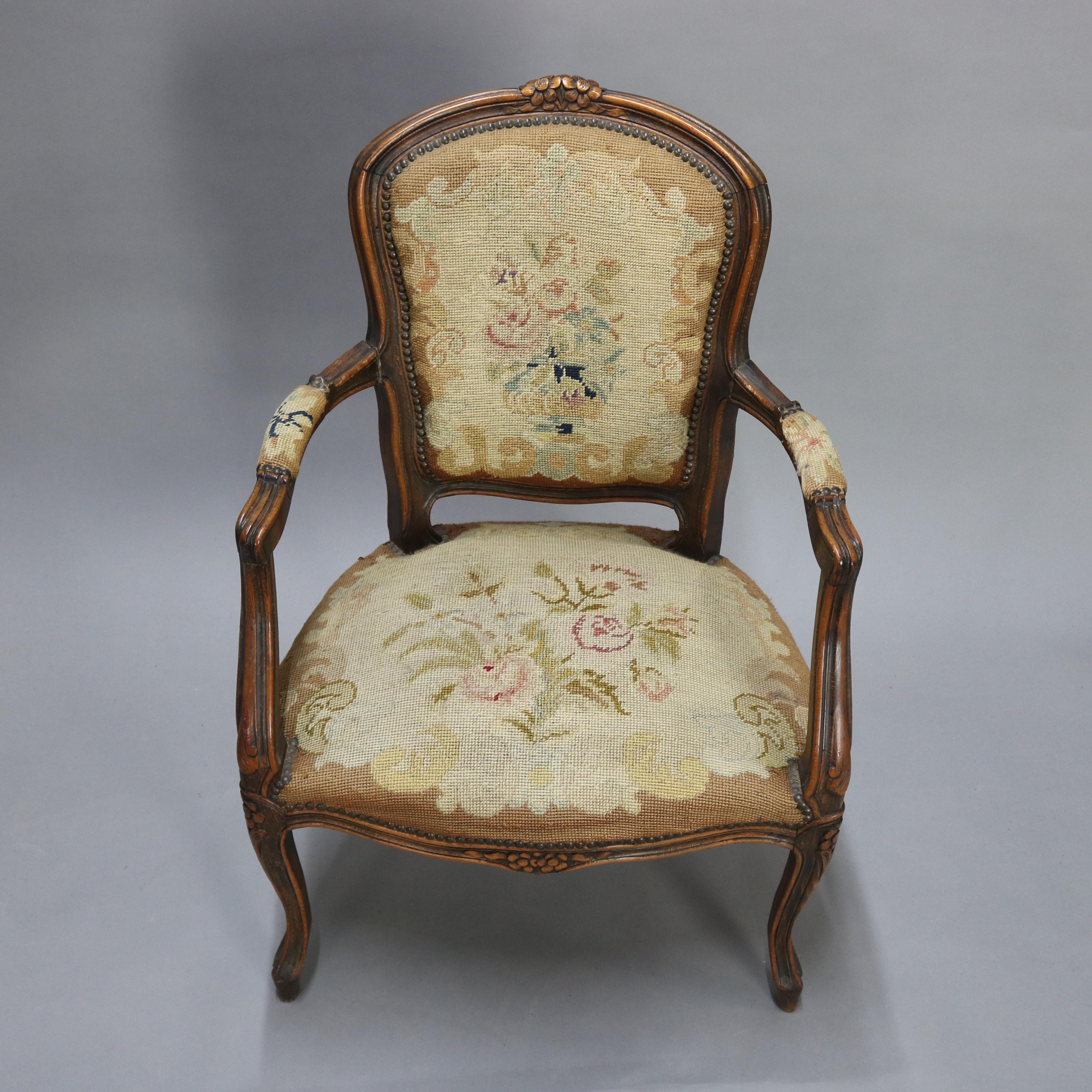 An antique French Louis XVI fauteuil armchair offers fruitwood frame with carved floral crest, apron and knees with floral panier de fleurs needlepoint back and seat, raised on cabriole legs, 19th century.

Measures: 43.5