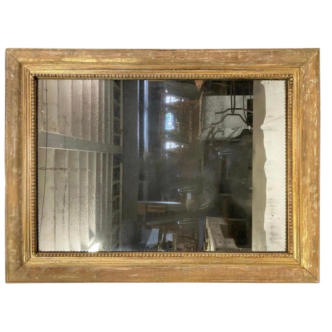 A simple yet elegant 18th Century French Louis XVI style giltwood wall mirror with a fine beaded border. The rectangular wall mirror has lost most of the gilt but retains a nicely weathered patina. Placed the mirror above a vanity in a powder room,