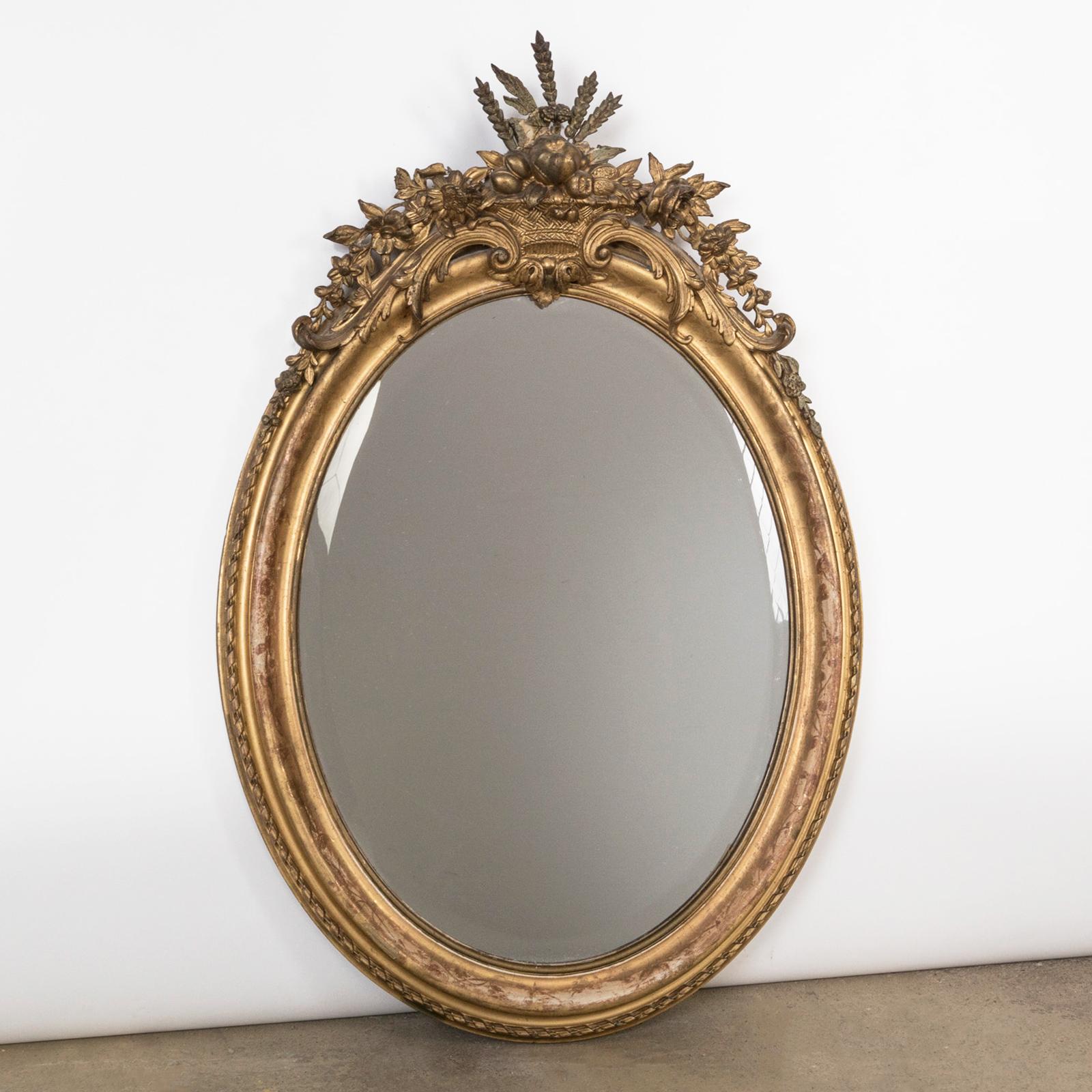 Antique 19th Century French oval gold leaf gilt mirror with a basket fruit and flower shaped crest.

A beautiful antique oval mirror that was made in France, circa 1880.

The mirror frame is decorated with an elegant top ornament in the form of