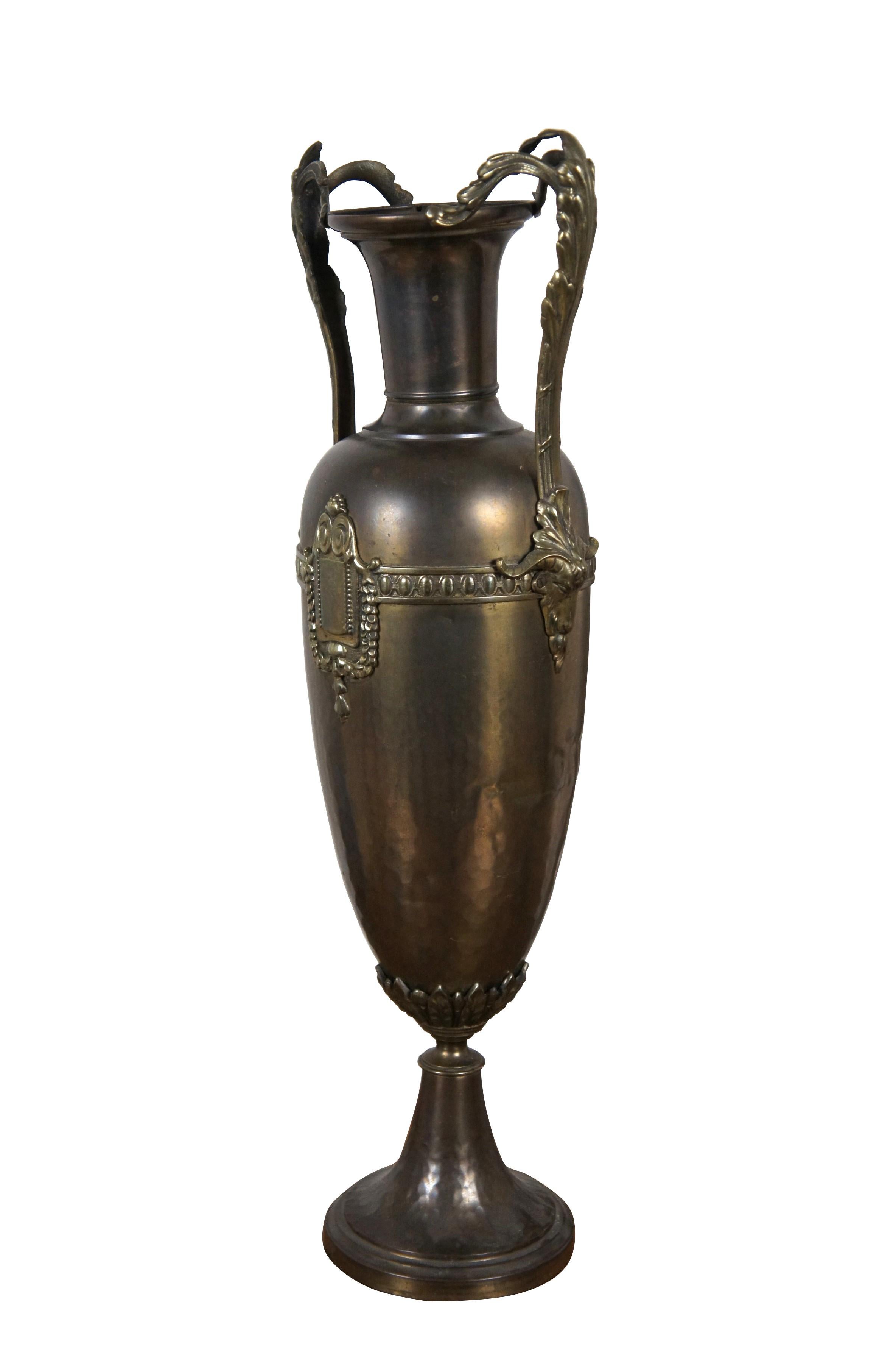 Coppia di vasi da camino / urne da trofeo in ottone martellato. Realizzato in ottone in stile neoclassico e Luigi XVI con basi rotonde, maniglie a doppia voluta, foglie d'acanto, scudi incorniciati e teste di ariete.

Dimensioni:
7,25