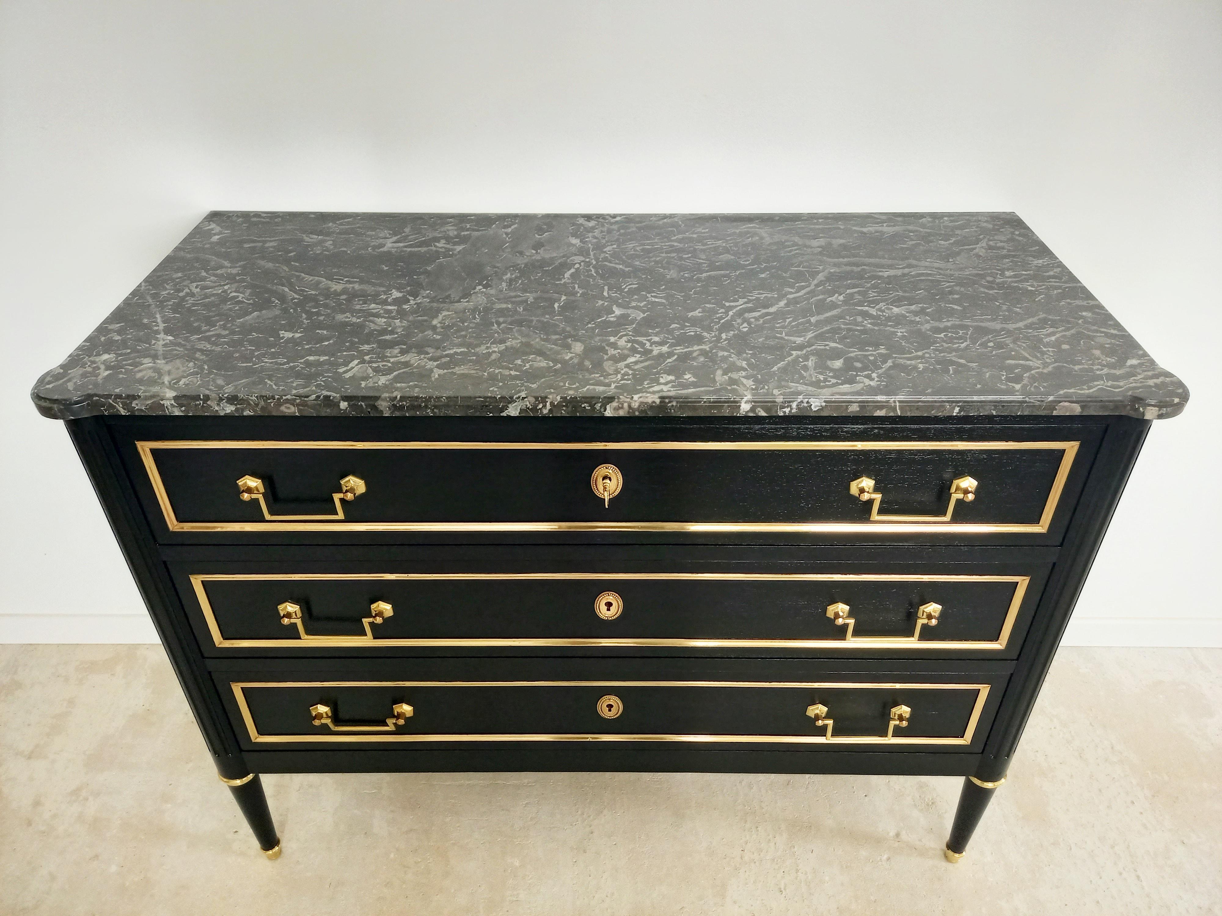 Antique French Louis XVI style Mahogany chest of drawers topped with a grey marble in perfect condition, fluted legs finished with golden bronze clogs.
Three dovetailed drawers with brass details.
  