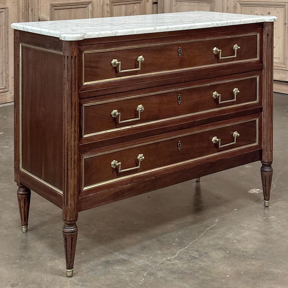 Antique French Louis XVI Mahogany Commode with Carrara Marble incarna il concetto di eleganza su misura!  L'esotico mogano importato conferisce una ricchezza che non si può negare, definita da modanature rettilinee che includono finiture in ottone e