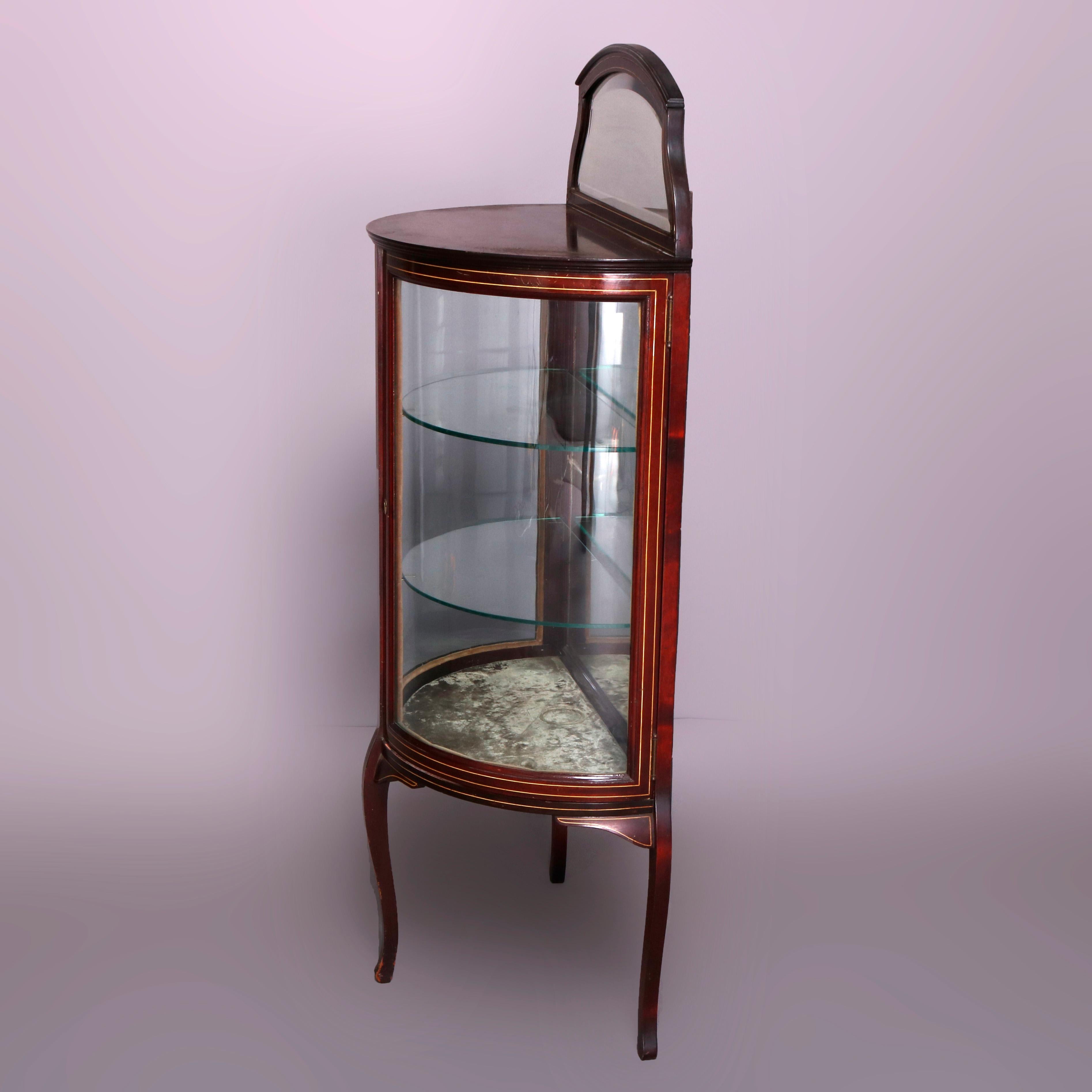 An antique French Louis XVI vitrine offers mahogany construction in demilune form having shaped and mirrored backsplash over single door cabinet with curved glass and mirrored interior, raised on cabriole legs, circa 1900.

Measures: 54.75