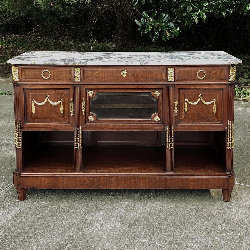 Antique French Louis XVI Mahogany Marble Top Buffet with Gilt Bronze Mounts represents the essence of the classical style celebrated especially during the latter years of the 19th century into present times. This example, rendered from exotic