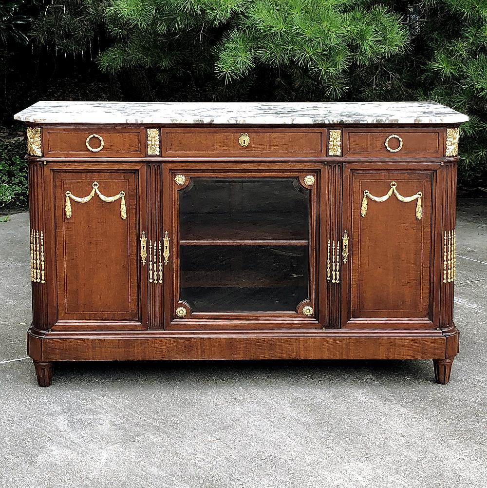 Antique French Louis XVI Mahogany Marble Top Buffet with Gilt Bronze Mounts represents the essence of the Classical style celebrated especially during the latter years of the 19th century into present times. This example, rendered from exotic