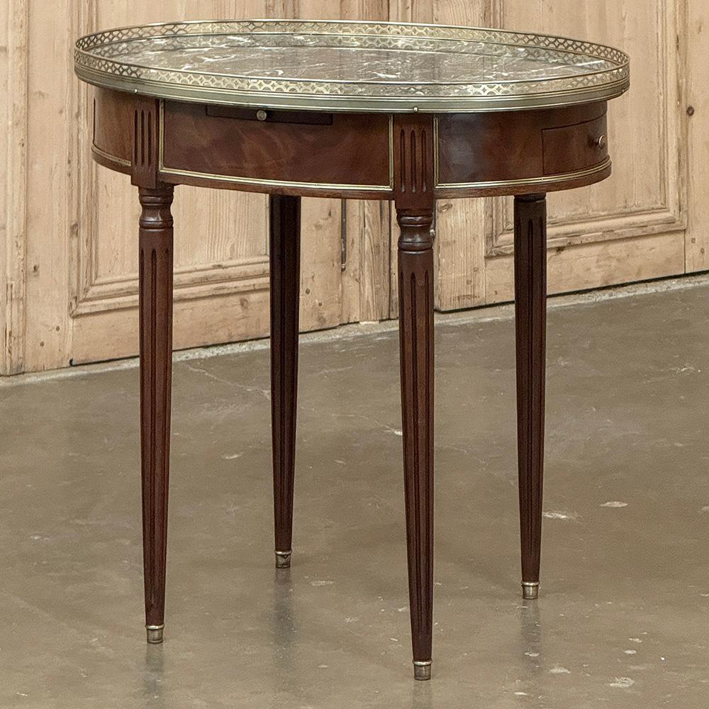 Antique French Louis XVI Mahogany Marble Top Oval Bouillotte Table represents an understated elegance that is perfect for the tailored yet refined decor.  Unusual to find in an oval shape, it was hand-crafted from exotic imported mahogany, it