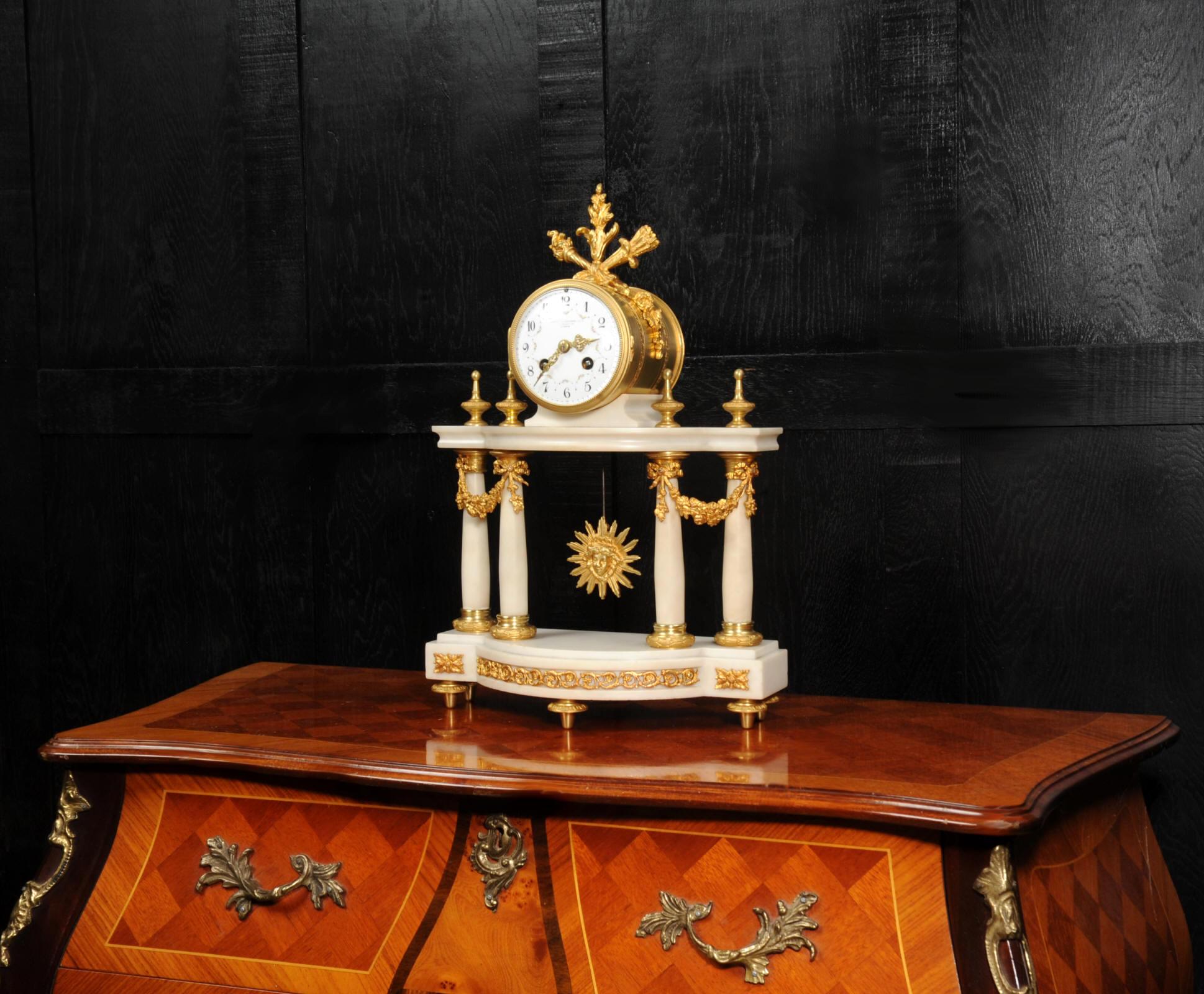 A beautiful Antique French portico clock retailed by the famous Goldsmiths and Silversmiths Co of Regent Street, London. It is of the classical style of Louis XVI, made of white marble mounted with ormolu (finely gilded bronze). The movement is held