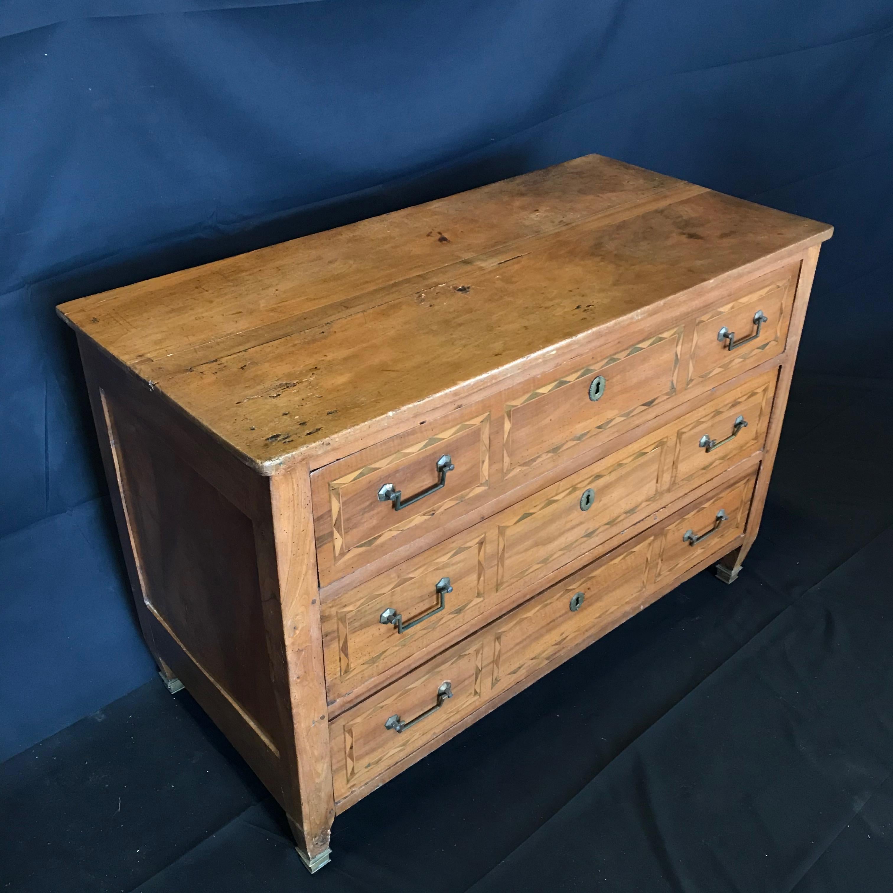 Wonderful antique French Louis XVI period walnut marquetry commode having three drawers and beautiful patina. The interior of the three drawers is oak. The work of marquetry is in walnut, with some parts dyed in ebony. There are original bronze