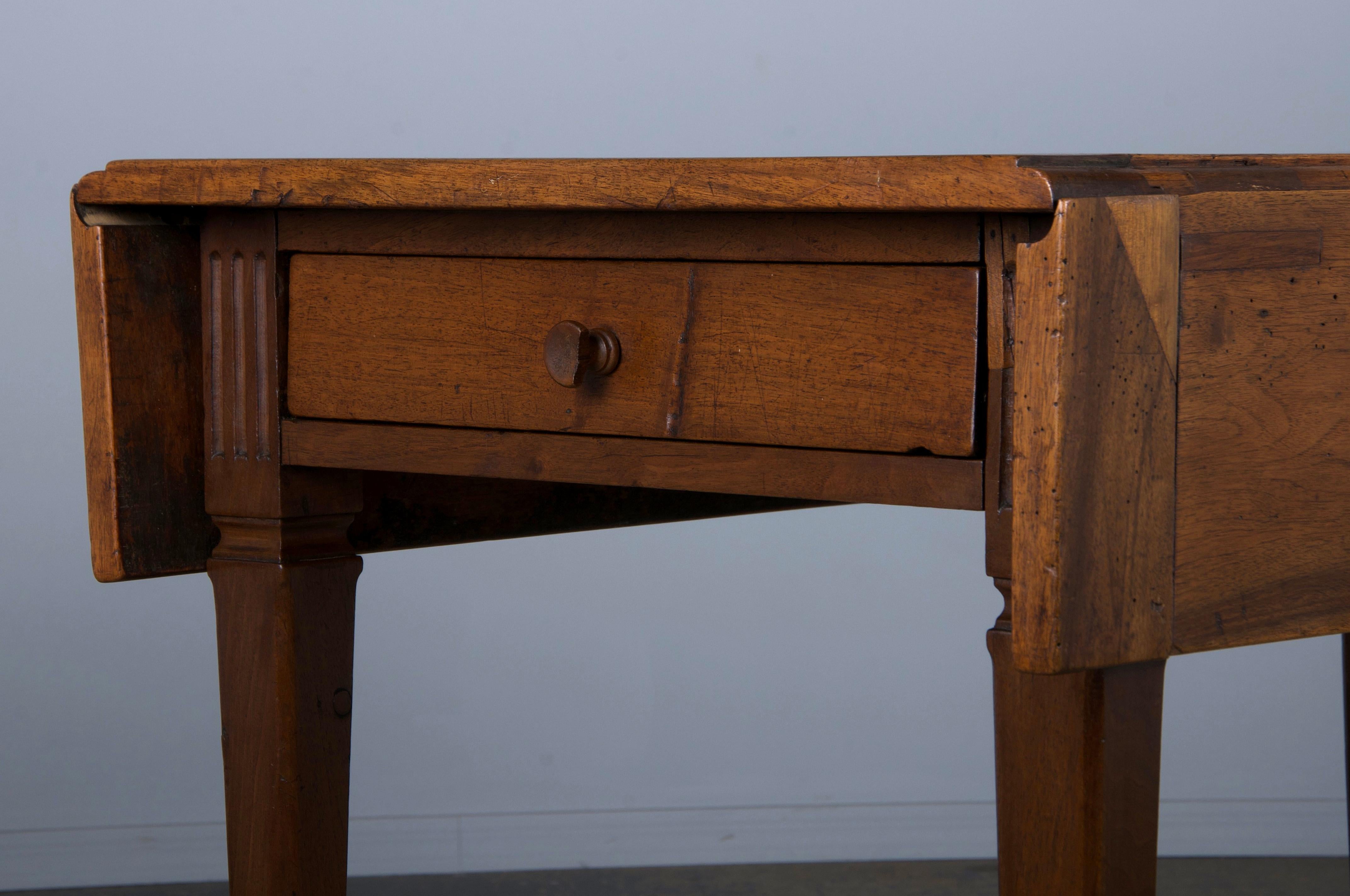 Charmante table à abattant française de la fin du XIXe siècle, de style néoclassique Louis XVI, provenant de Provence (France). Magnifiquement fabriqué à la main en noyer massif, il présente un étroit plateau rectangulaire avec deux feuilles