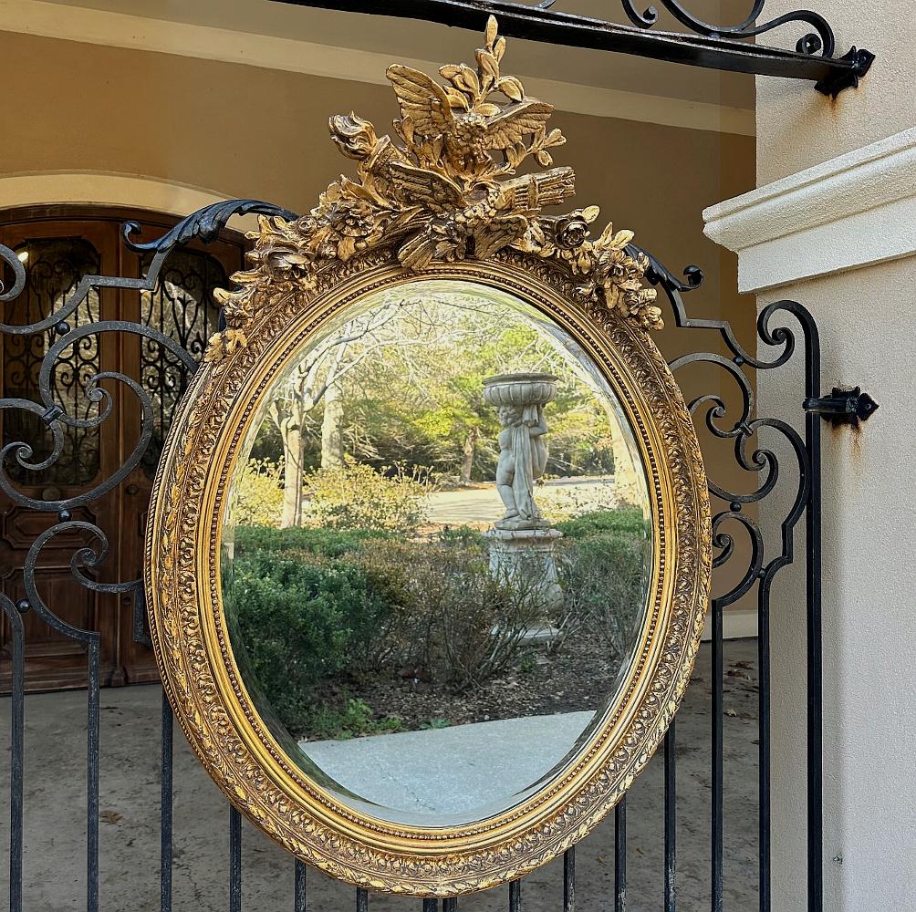 Antique French Louis XVI Oval Gilded Mirror is a stunning work of art with a classic and romantic theme!  Celebrating both the power of love and the beauty of nature, the design shows the influence of the Louis XVI style with the timeless expression