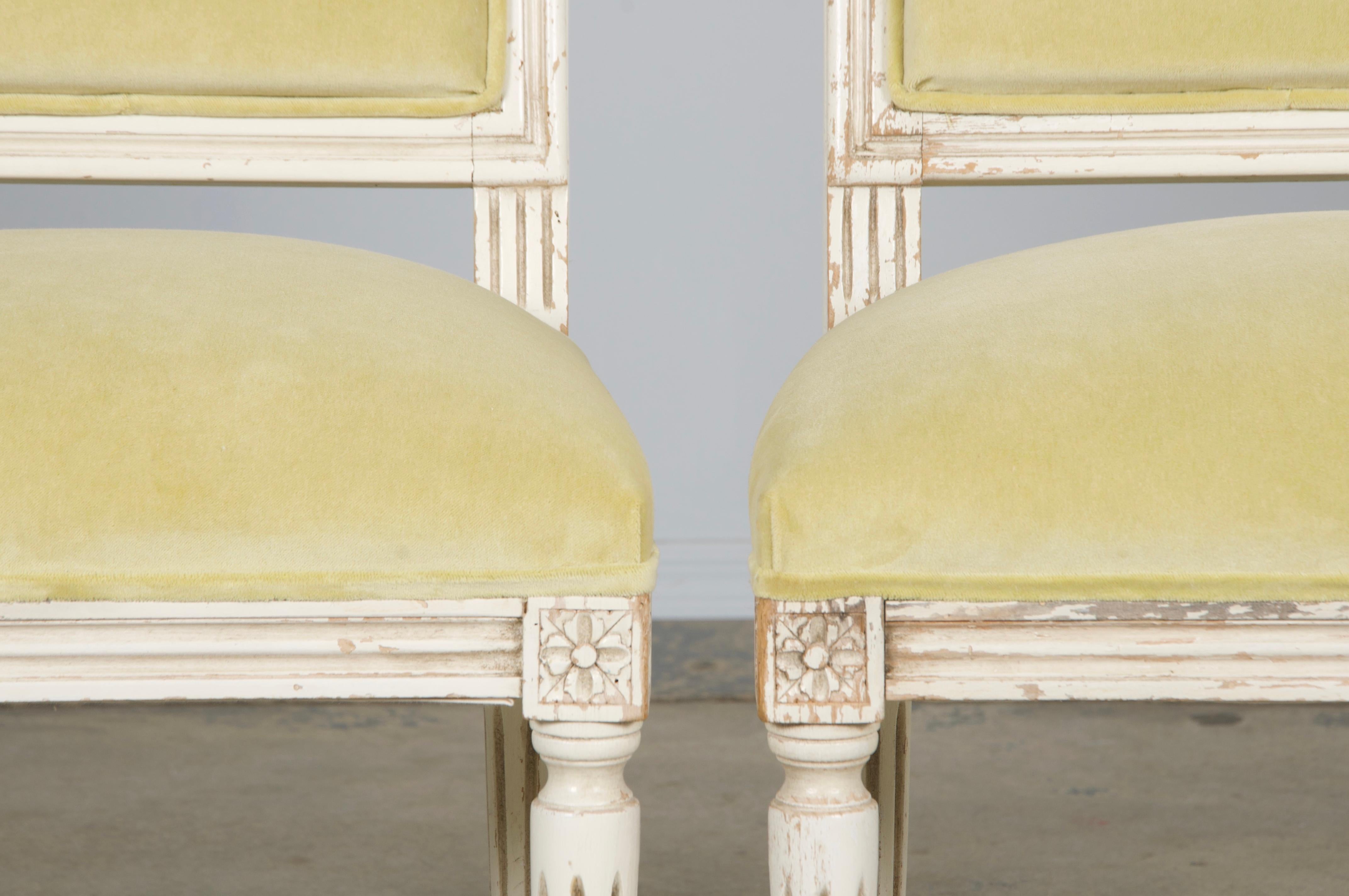 A charming pair of late-19th-century Louis XVI-style accent chairs, sourced from Provence, France. Each features a hand-crafted maple frame with a square back, hand-painted in creamy antique white with a naturally distressed patina that reveals