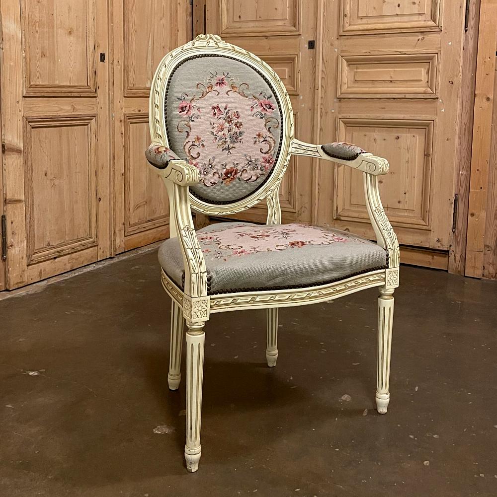 Ce fauteuil ancien français Louis XVI peint avec tapisserie à l'aiguille est aussi élégant que possible, mais aussi étonnamment confortable ! Le dossier ovale est profilé pour épouser la forme du dos, et le siège de taille généreuse est encadré par