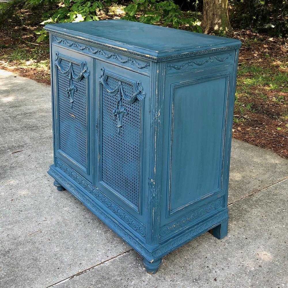 Antique French Louis XVI painted cabinet is a lovely Provencal blue, a color that is seen in abundance in the South of France! This cabinet features caned doors with flower basket carvings overlaid atop the caning, and tailored neoclassical