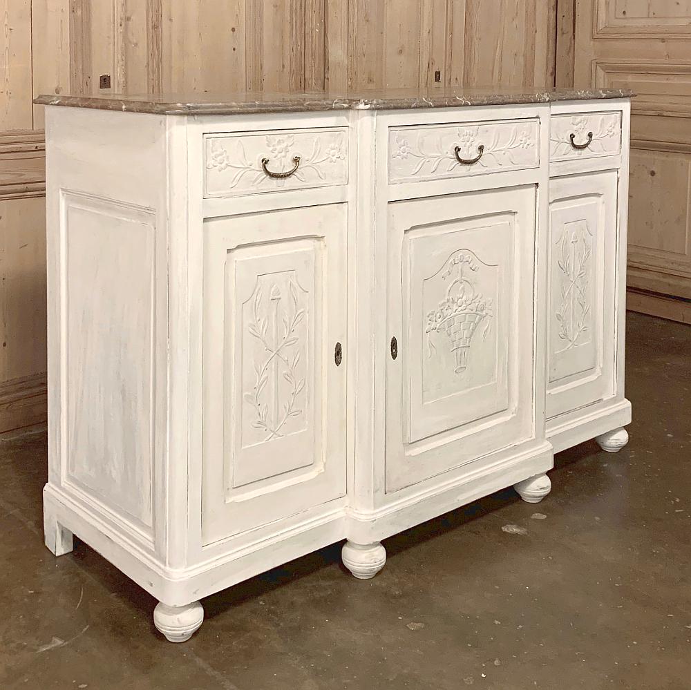 Antique French Louis XVI painted marble-top buffet is a superlative expression of tailored neoclassical architecture and embellishment, with raised relief carvings of a basket bursting with flowers on the center cabinet door, which has been stepped