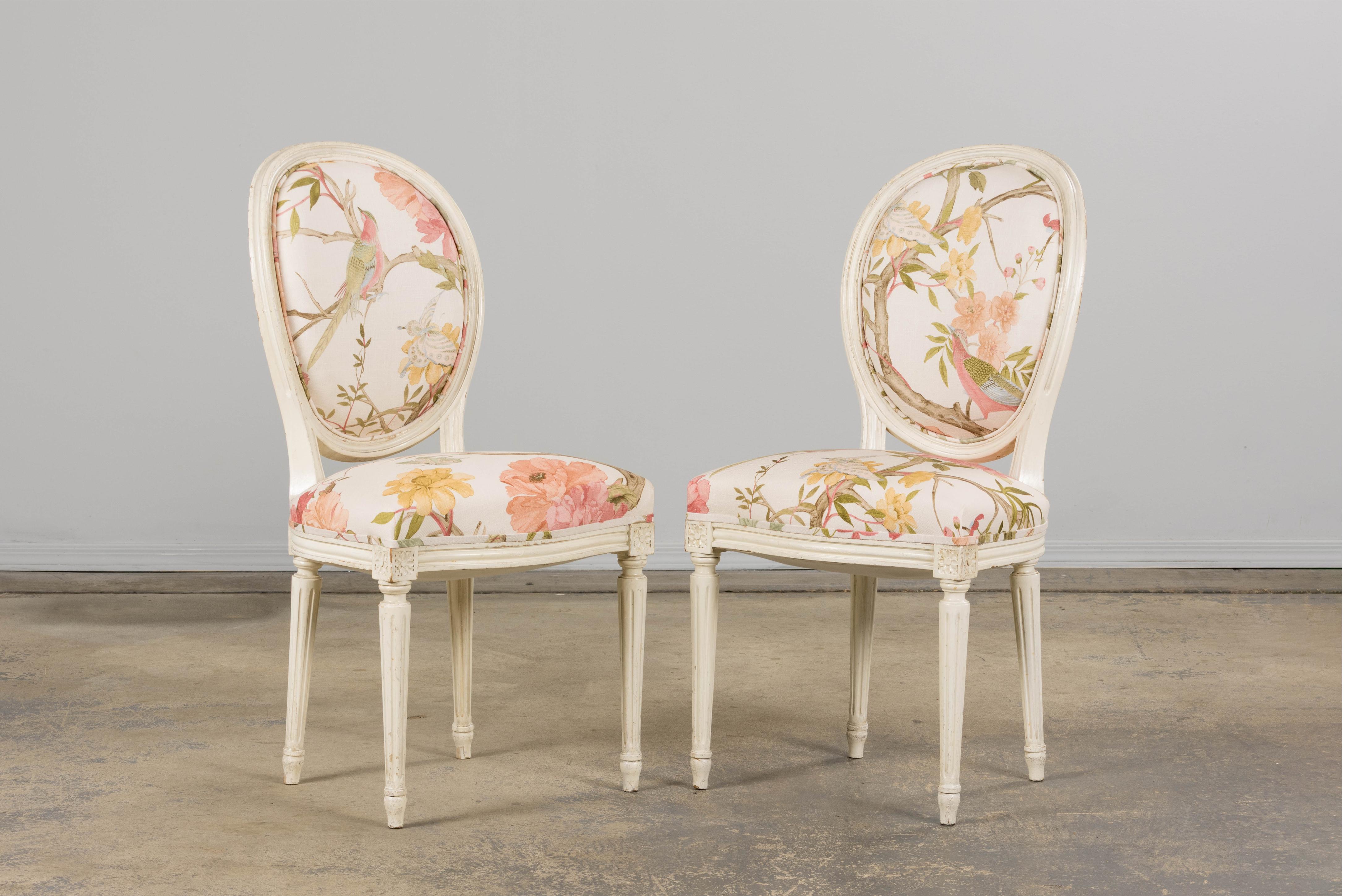 A romantic pair of late 19th-century Louis XVI-style accent chairs, sourced in Provence and reupholstered in an expressive Chinoiserie-inspired cotton. The hand-carved frames feature oval backrests with refined tapered legs, fluted columns, and