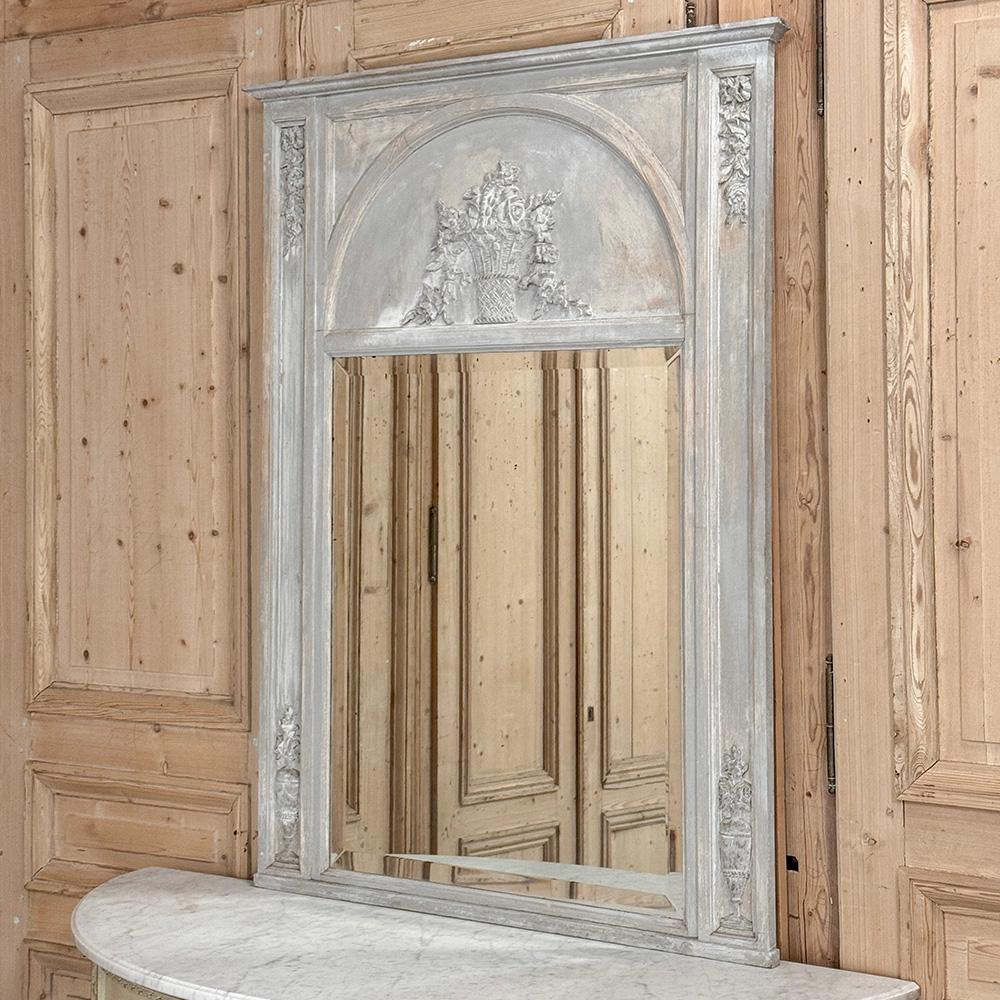 L'ancien miroir Trumeau peint de style Louis XVI est une célébration du renouveau du style néoclassique qui remonte à la Grèce et à la Rome antiques.  Le cadre rectiligne est rehaussé par un panneau arqué au-dessus du miroir biseauté français, qui