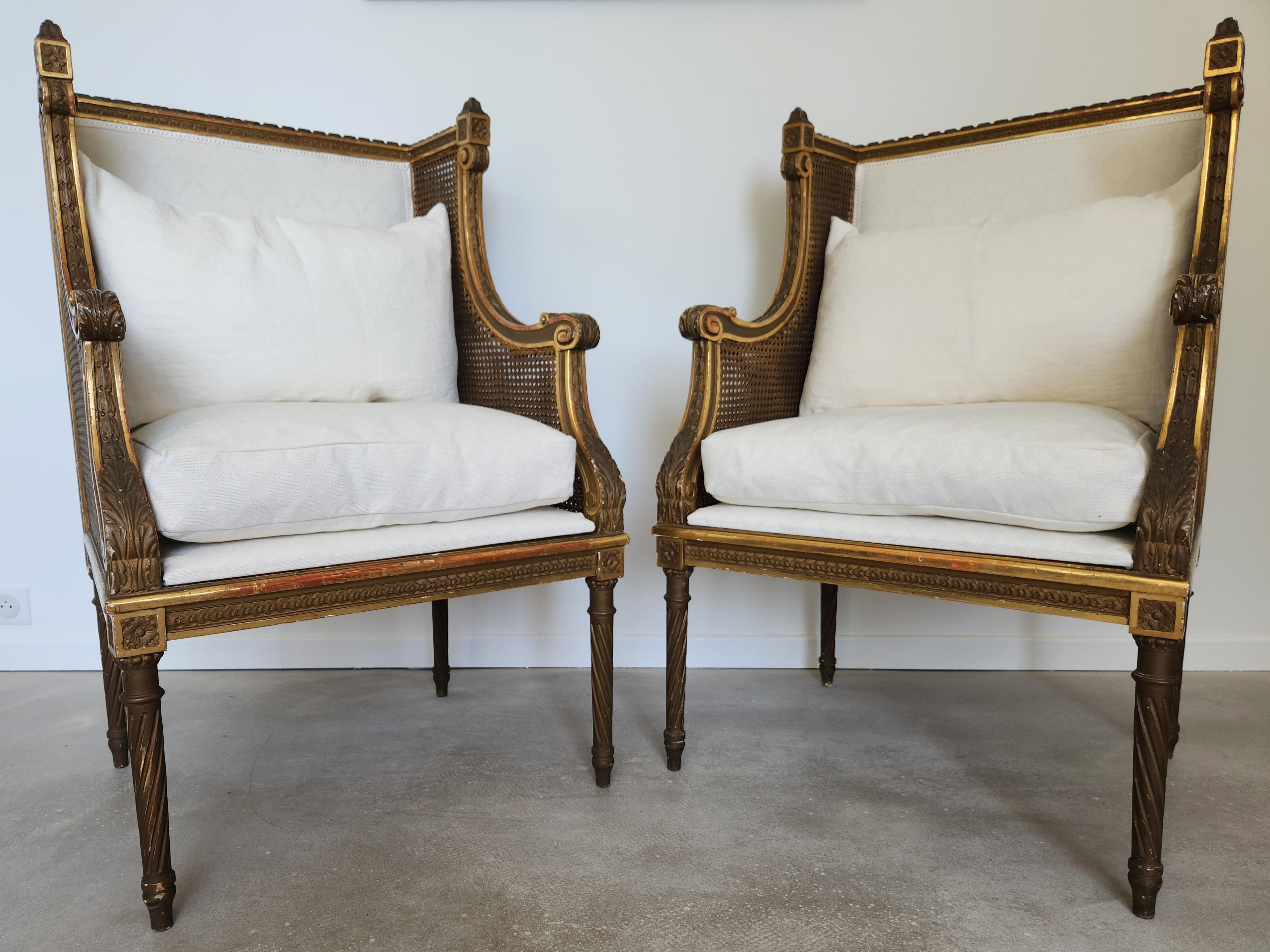 Rare pair of Louis XVI period armchairs in gilded wood with original double cane armrests. 
The fluted turned wood legs and hand-carved details are the result of remarkable craftsmanship.
The stable structure and patinated gilding demonstrate their