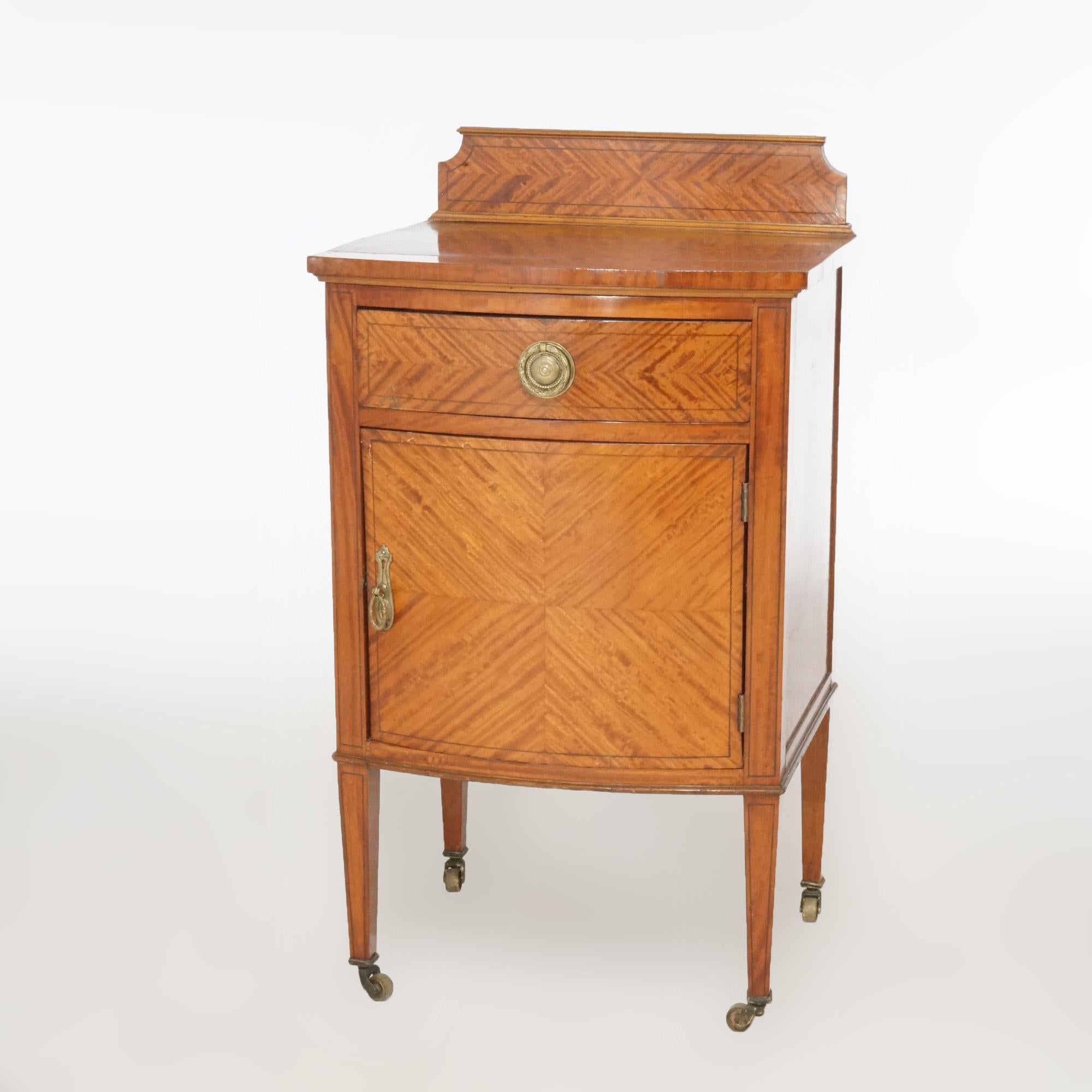An antique French Louis XVI side stand offers satinwood construction with bookmatched facing and having upper backsplash over bow front case with drawer and single door cabinet, raised on square tapered legs, c1920

Measures- 35.75''H x 19.75''W x