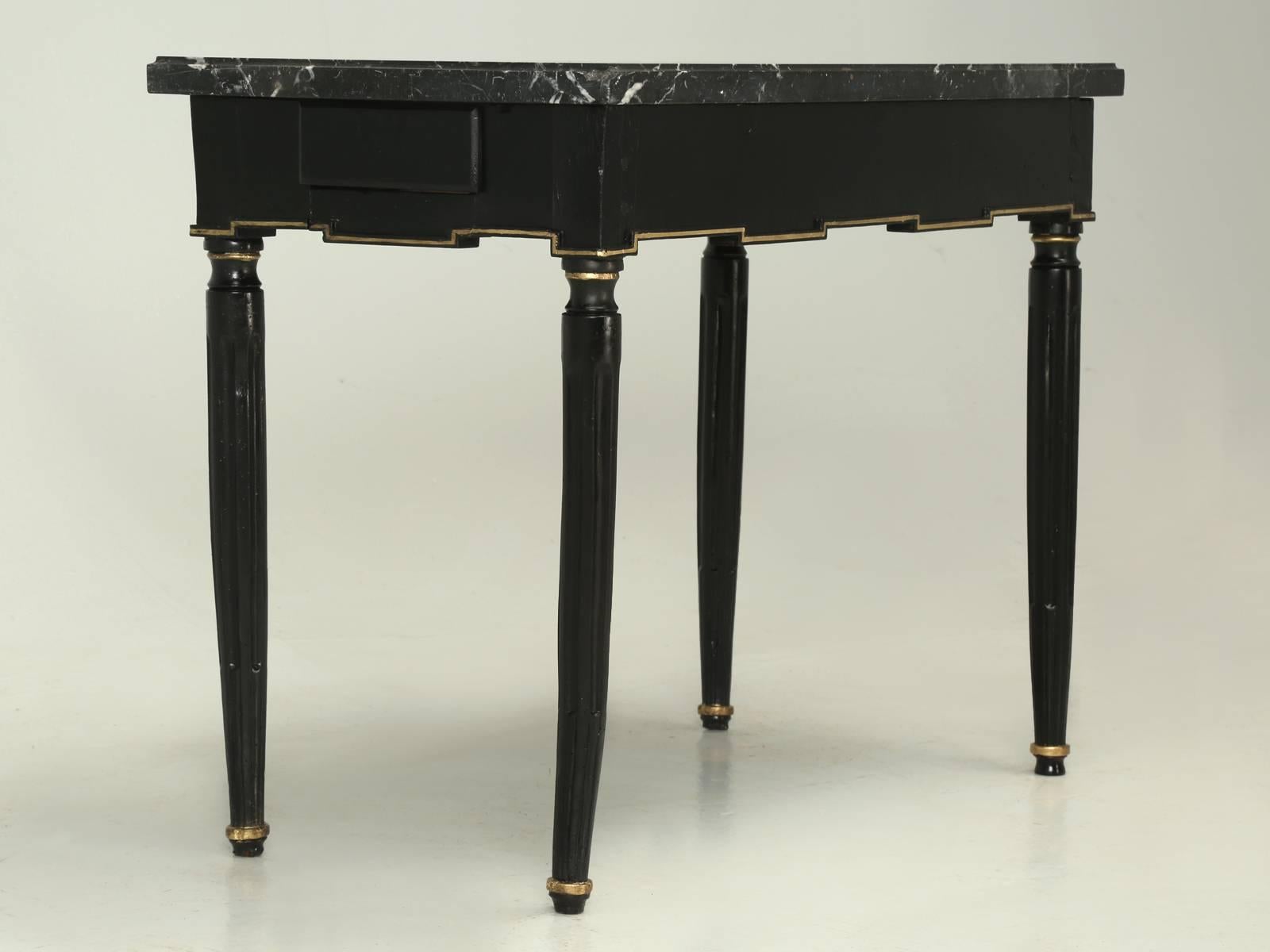 Antique French Louis XVI style end or side table, done in an ebonized finish, with gold leaf accents. Please look carefully at the legs, for this antique French Louis XVI style end table, is so old that the legs are slightly bowed. The expert in