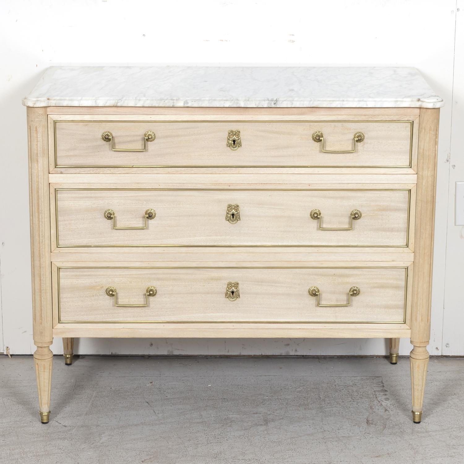 An early 20th century French Louis XVI style bleached mahogany three-drawer Parisian commode, circa 1920s. This beautiful antique bleached commode features the original Carrara marble top with cookie cutter corners above a case with three full-sized