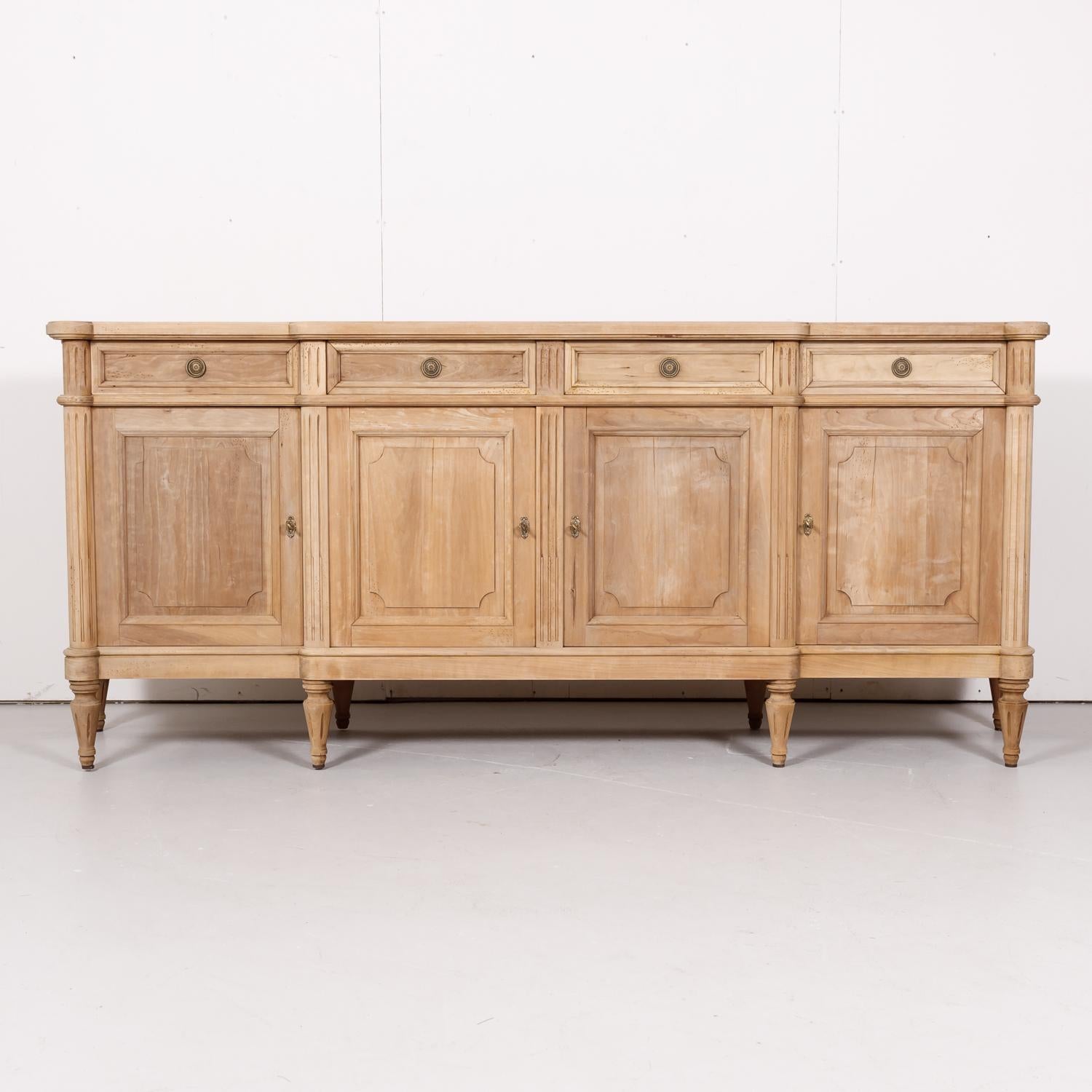 Antique French Louis XVI style enfilade buffet handcrafted in the Île de France region of walnut having a bleached finish, circa 1920s. The curved, shaped top sits above two center drawers, flanked by slightly stepped-back drawers on each side.
