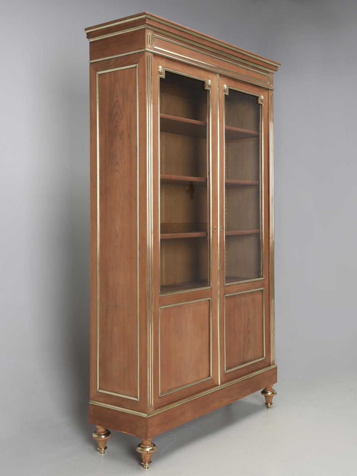 Antique French Louis XVI bookcase (bibliotheque), or china cabinet, probably made from solid mahogany. All of the decorations are constructed of real brass and are not merely painted gold. The mahogany cabinet itself, has been carefully hand-sanded