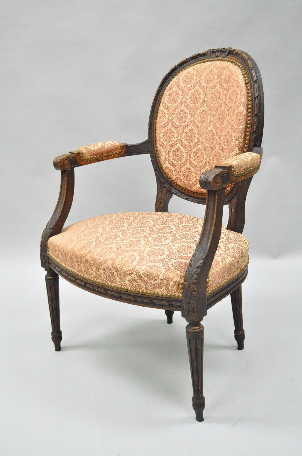 Antique French Louis XVI style bow carved walnut Fauteuil fireside arm chair. Item features a solid carved walnut frame, bow carved crest, reeded and tapered Legs, upholstered armrests, classic Louis XVI Form. Circa Early 1900s, France.