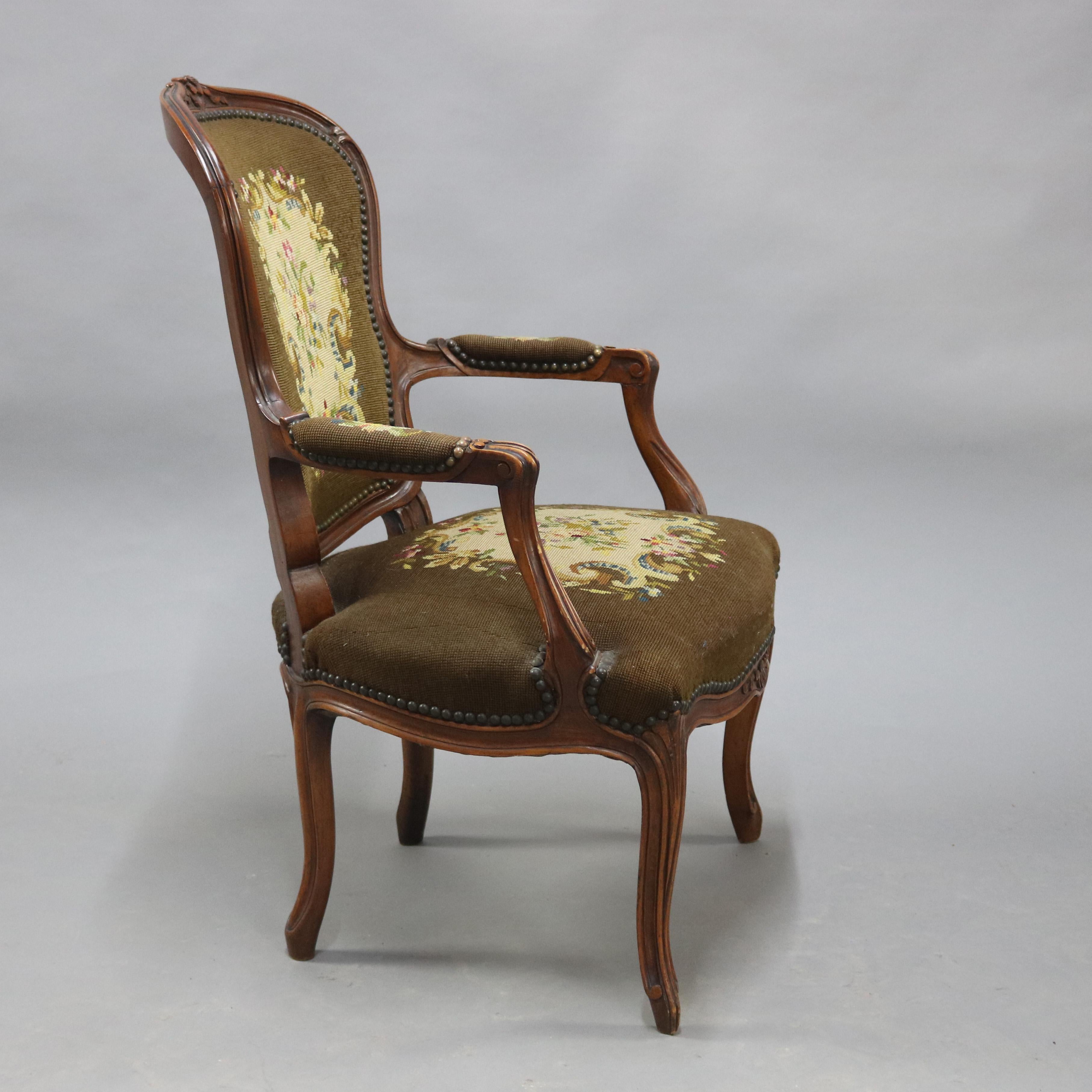 An antique French Louis XVI style armchair offers carved fruitwood frame raised on cabriole legs and having floral needlepoint back, seat and arms, circa 1900

Measures: 36