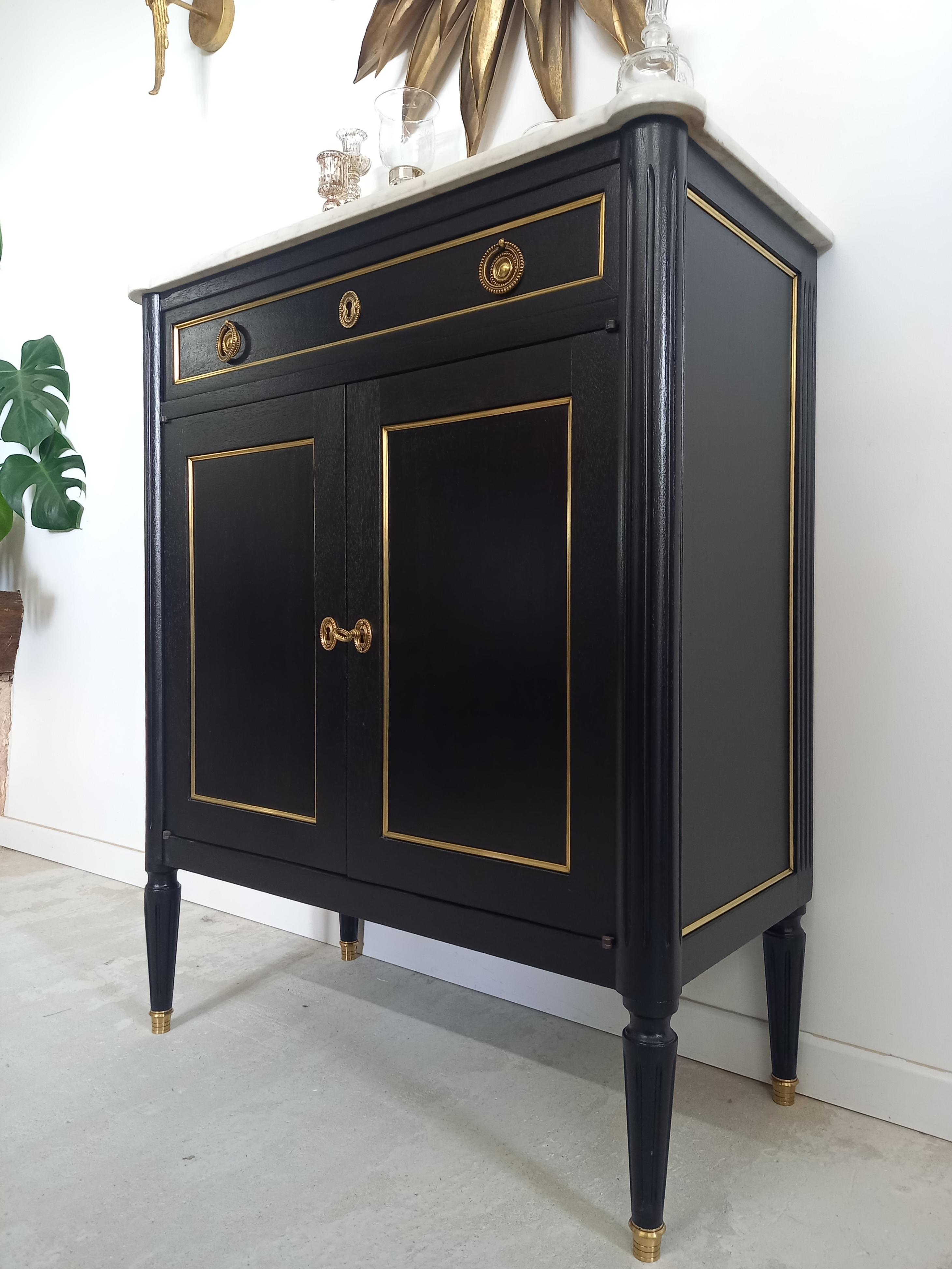 Antique French Louis XVI style bar buffet topped with a white Carrara marble, fluted legs finished with golden bronze clogs.
One dovetailed drawer, two doors and a practical storage space thanks to its height-adjustable shelves.
Perfect to create a