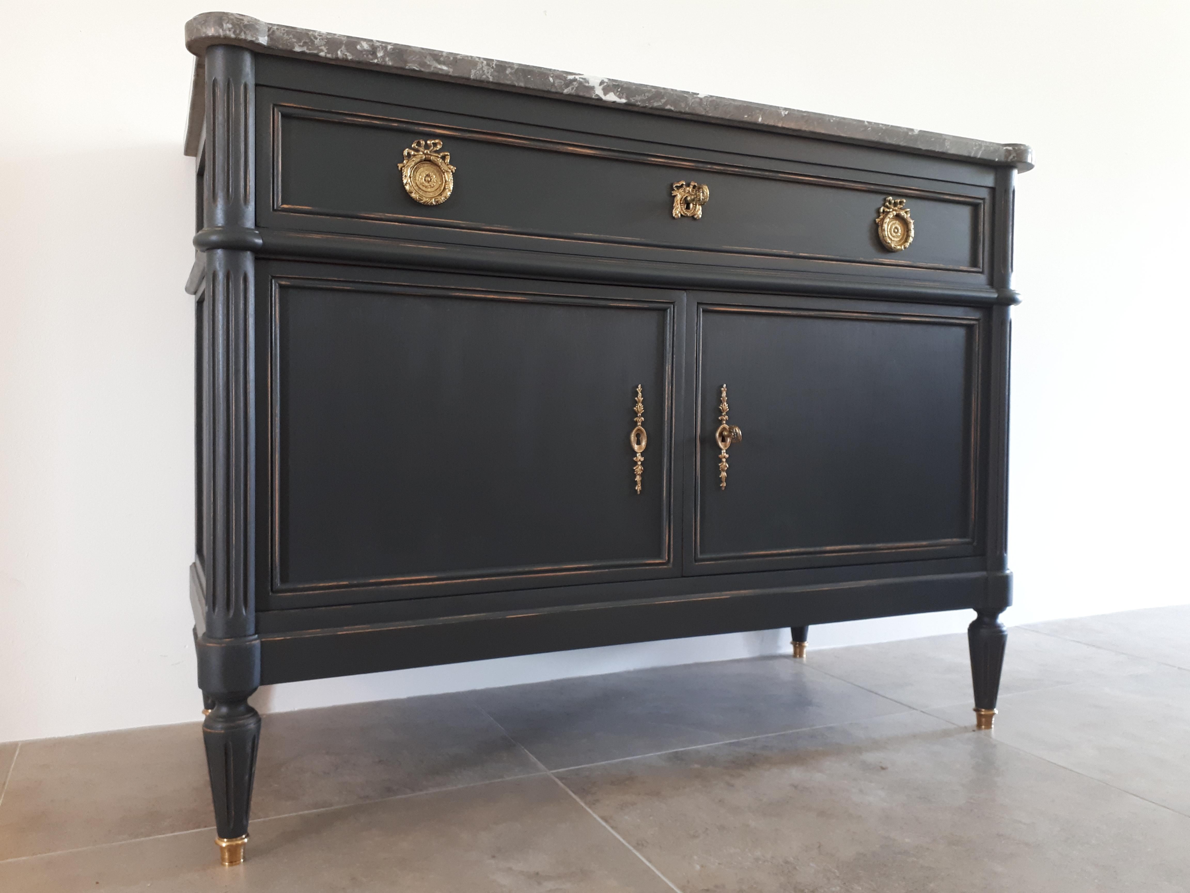 Antique French Louis XVI style chest of drawers topped with a grey marble, fluted legs finished with gilded bronze clogs.
A dovetailed drawer and two doors with gilded bronze details. Two keys.
   