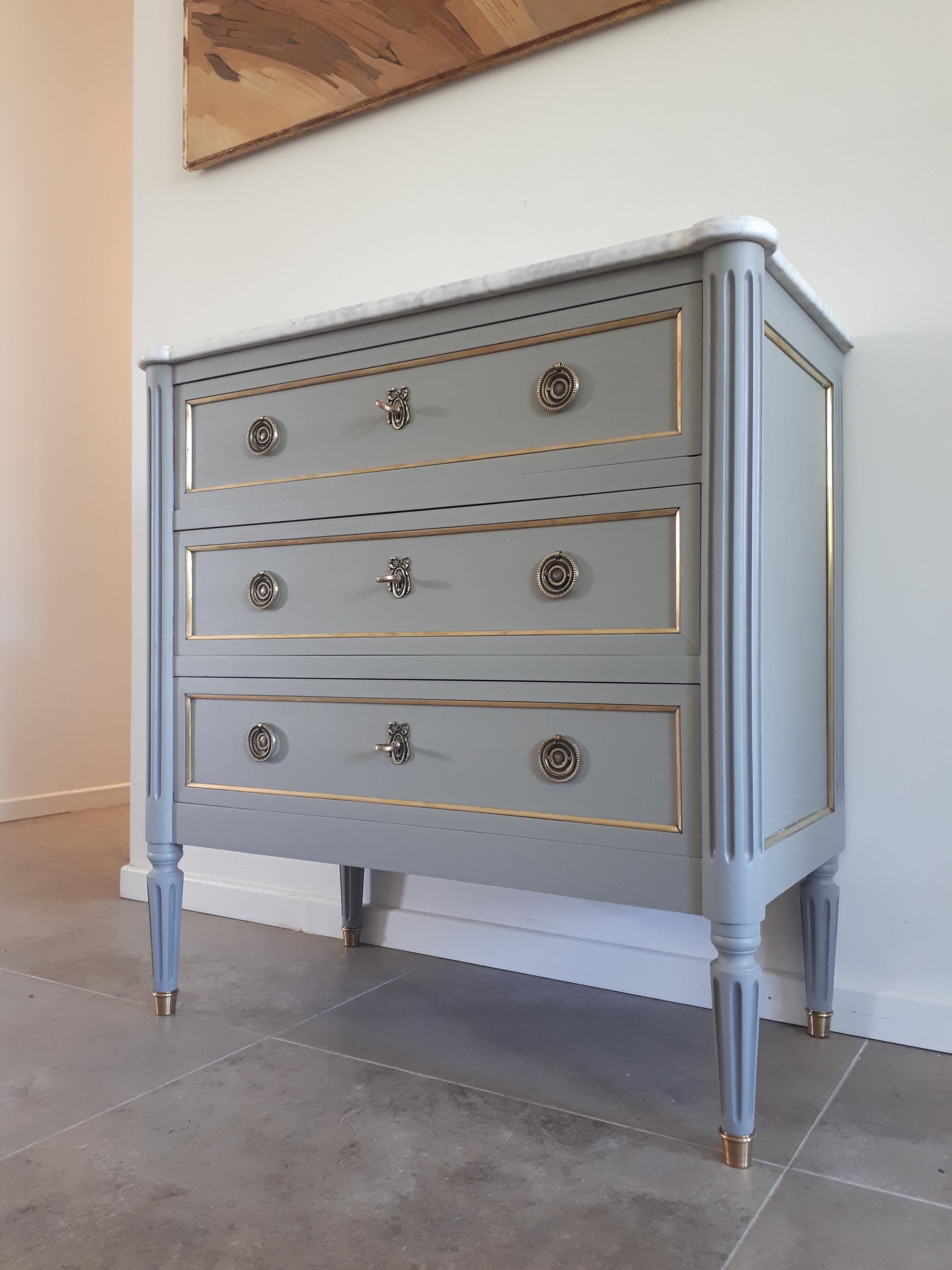Antique French, Louis XVI style chest of drawers topped with a white Carrara marble, fluted legs finished with golden bronze clogs. 
Three dovetailed drawers with brass details, and three keys.

Note that two small notches in the marble top had been