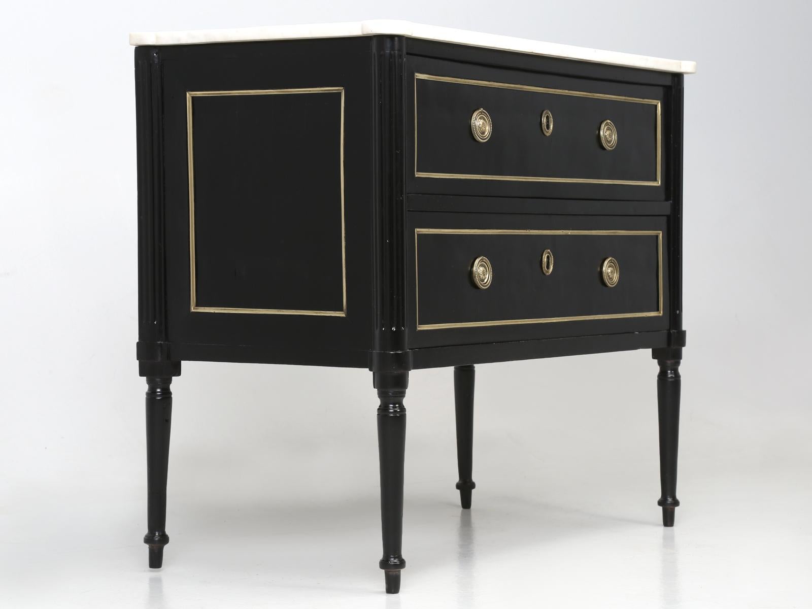 Antique French Louis XVI style mahogany cabinet that was ebonized. There are hairline cracks in the old finish, although admittedly they are difficult to see and certainly are no where near as visible as an old marble repair. The drawers function
