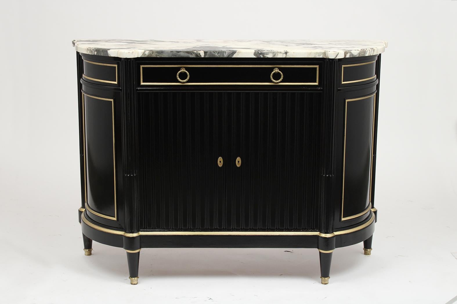 This antique French Louis XVI style server is made out of mahogany wood and comes with its original beveled marble top. This server has been professionally refinished in ebonized color, gilt molding accents, and a lacquered finish. This server has a