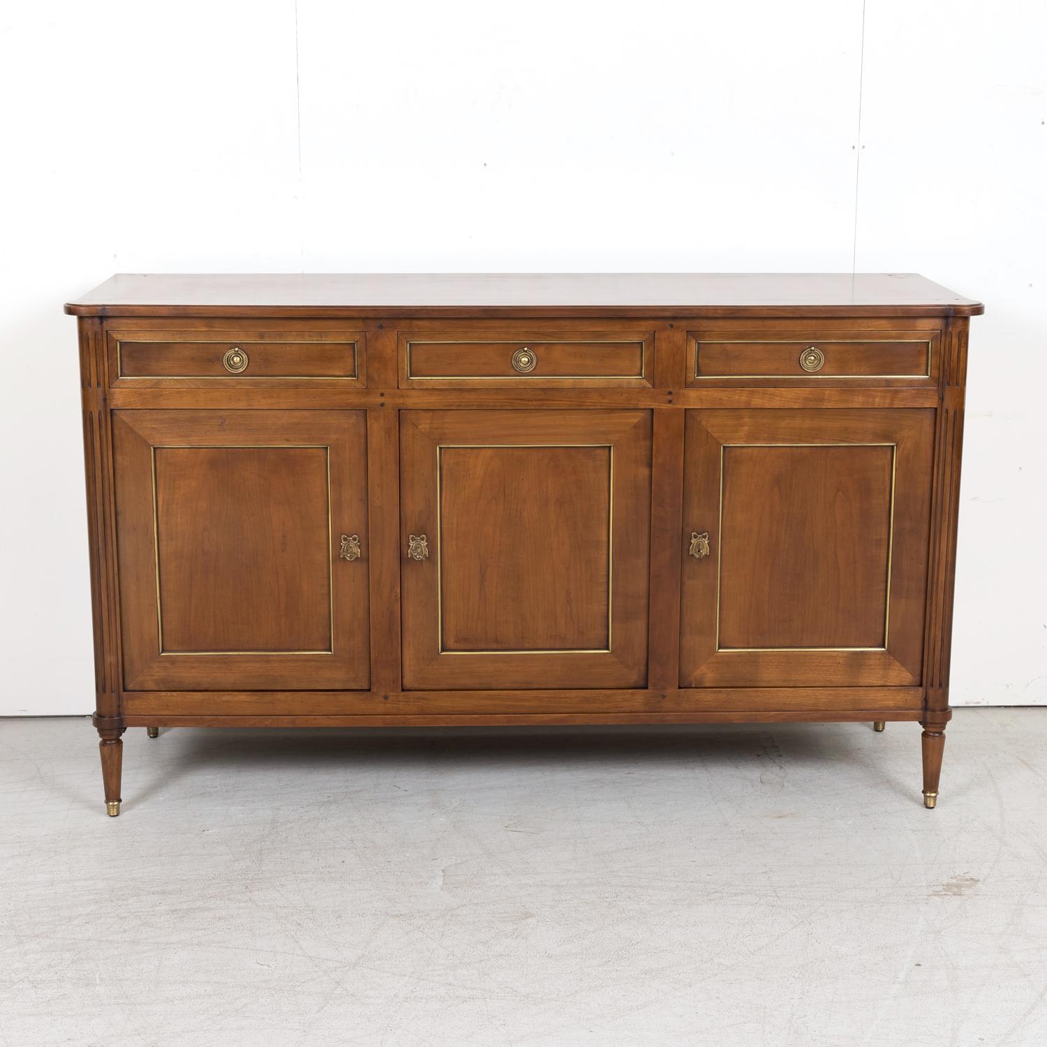 Antique French Louis XVI style solid cherry enfilade buffet, circa 1920s. This elegant Parisian enfilade with its straight lines and wonderful patina has a slightly overhanging top with cookie cutter corners atop three drawers over three paneled