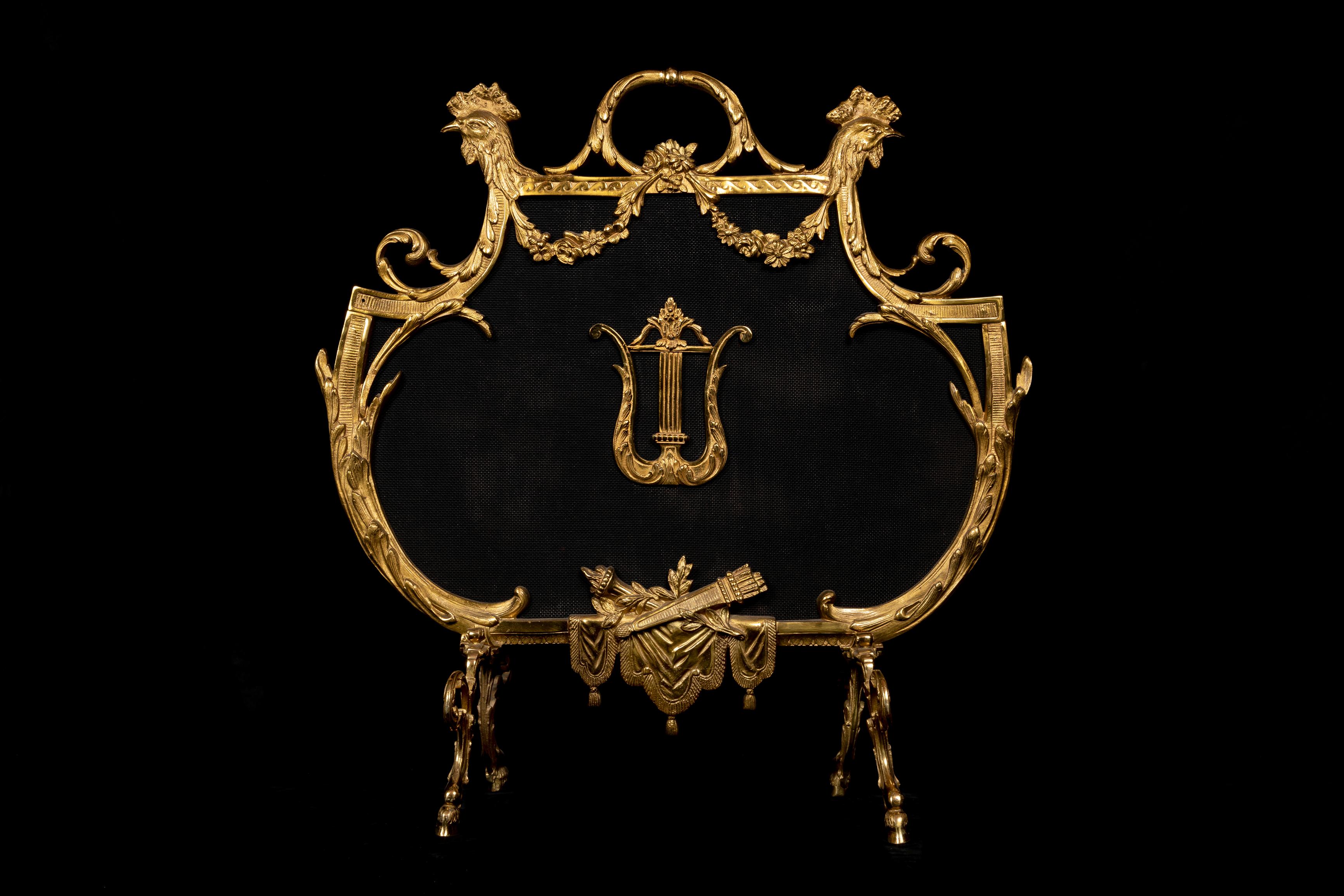 A Fine and Unique Antique French Louis XVI Style Gilt bronze fire screen of superb quality embellished with figural masks of roosters, floral wreaths and finally adorned with a gilt bronze lyre in the center.