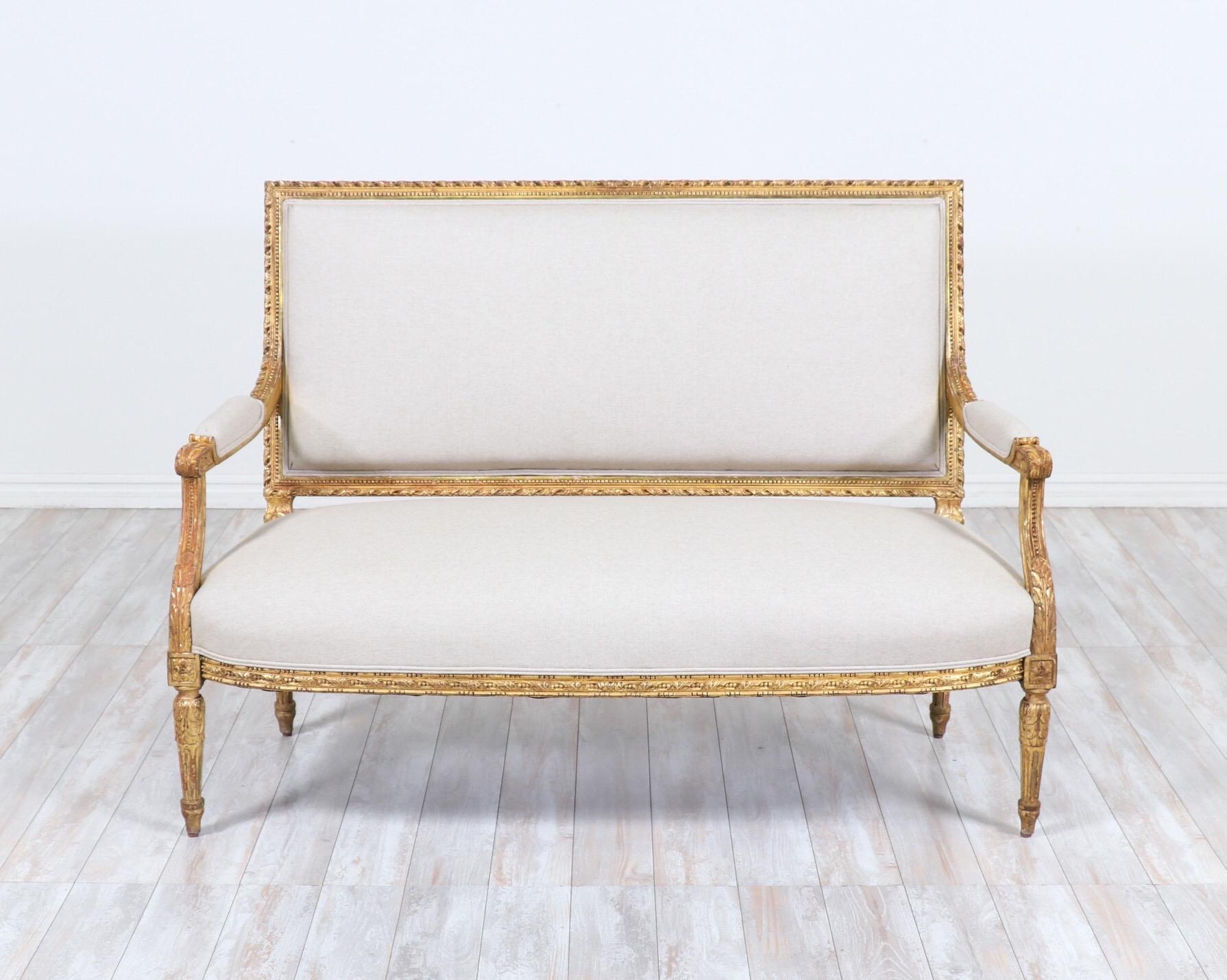 Exquisite, French 1920s Louis XVI-style giltwood settee with new cotton canvas linen upholstery.

Simple lines, intricately carved decorations and original 22-karat gold-gilding define this elegant French settee. 

The gilt finish is naturally