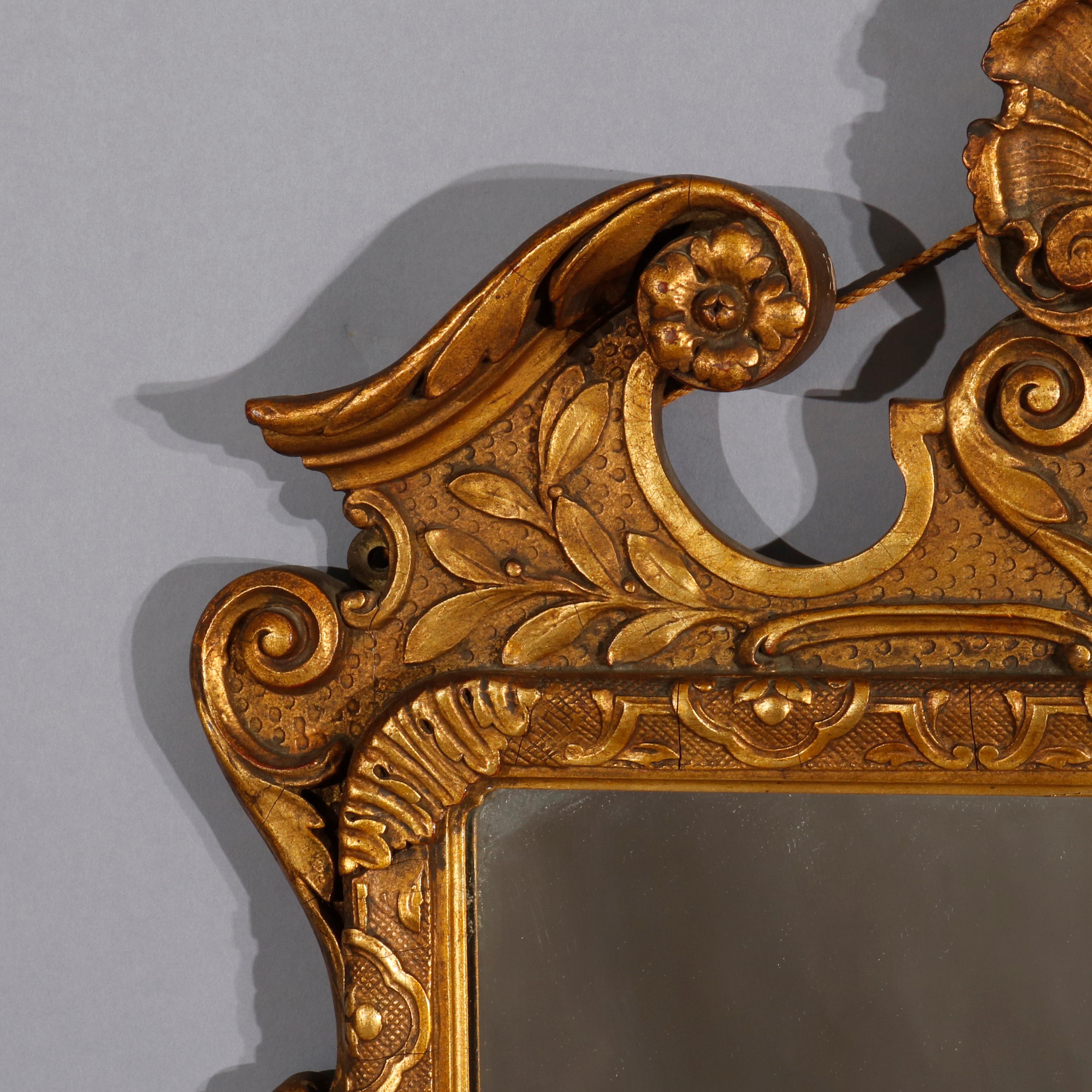 An antique French Louis XVI style wall mirror offers giltwood frame with broken arch crest having central shell cartouche surmounting frame with foliate and scroll embossed decoration and shell at base, 20th century.

Measures: 39.75